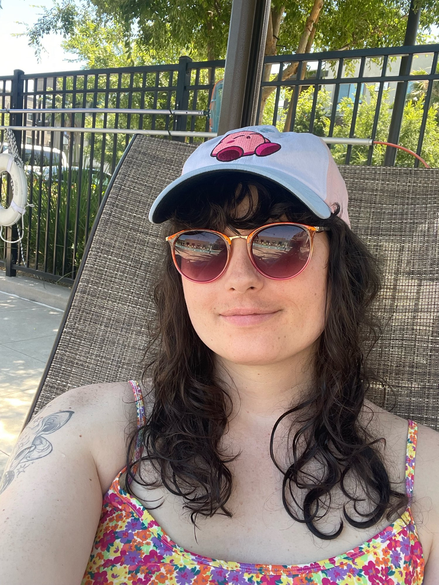 Moonreed wearing a blue and pink Kirby hat, sunglasses, and a colorful floral bikini