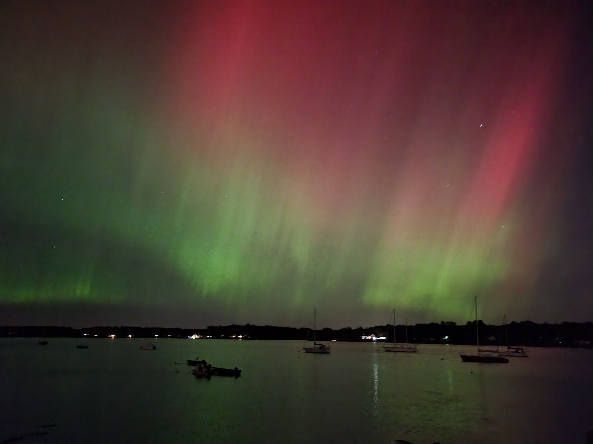 Picture of the aurora with red and green colors over a lake