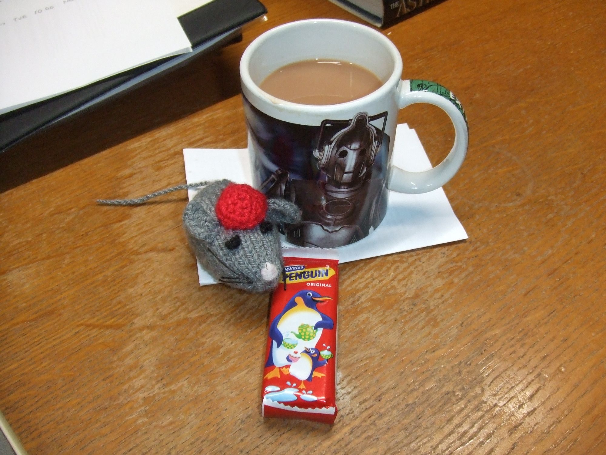 A dr who mug with tea, chocolate bar and woolen mouse