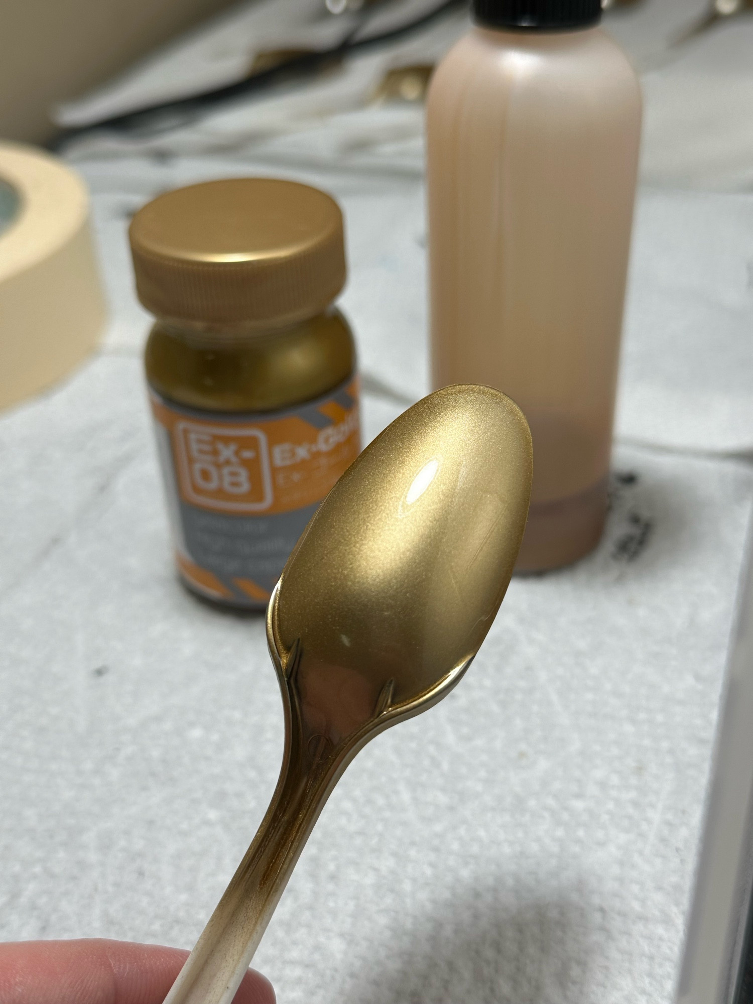 A photo of an airbrushed plastic spoon, sprayed with GaiaNotes EX-Gold