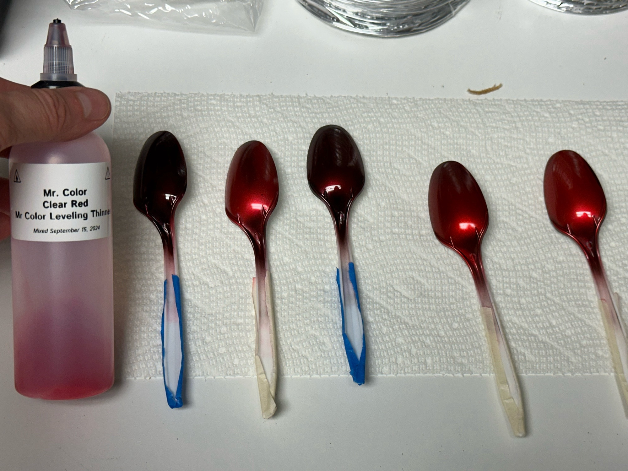 Five airbrushed plastic spoons sprayed with Mr. Color Clear Red