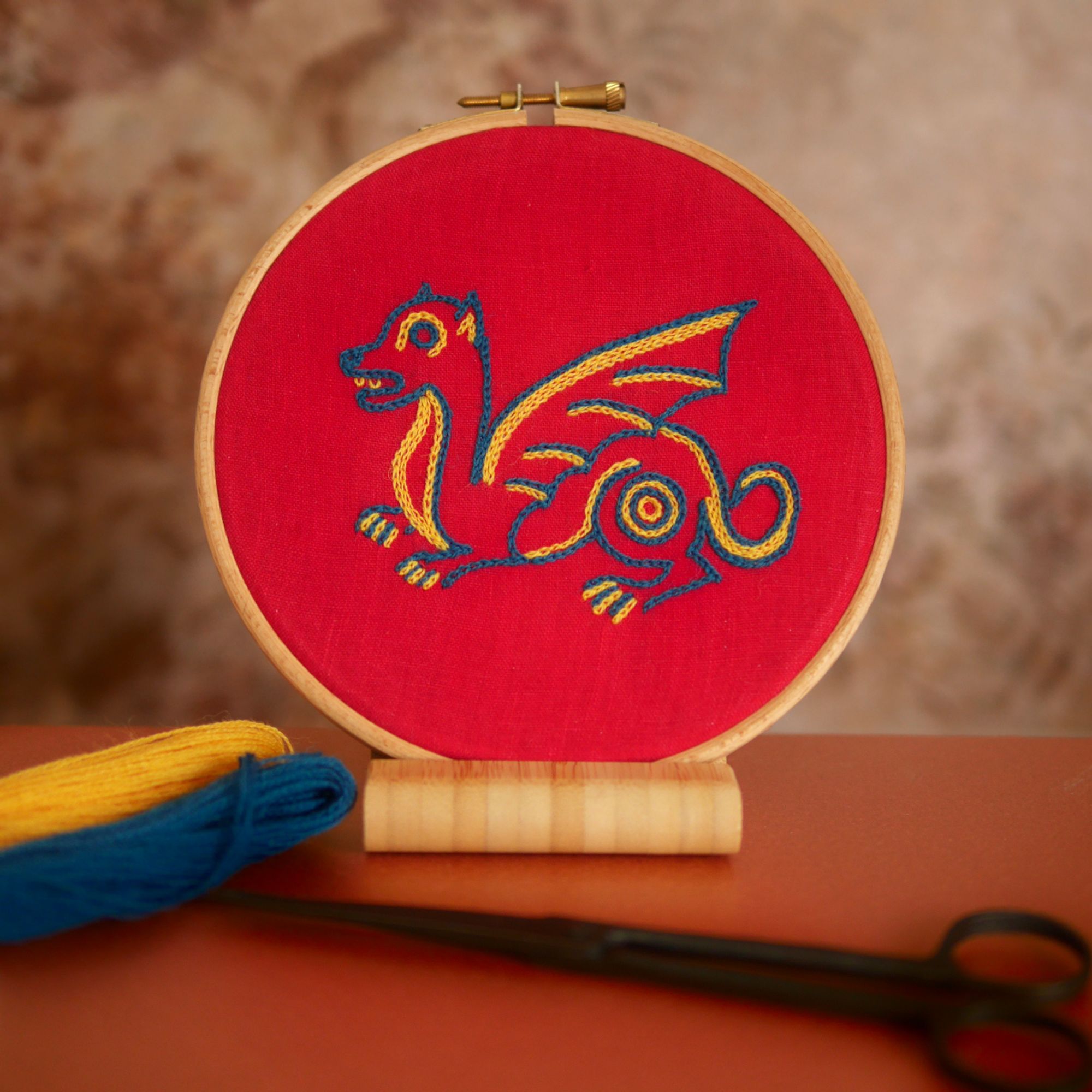 Broderie colorée dans un tambour.
Il s'agit d'un dragon mignon dans un style naïf et coloré sur toile rouge