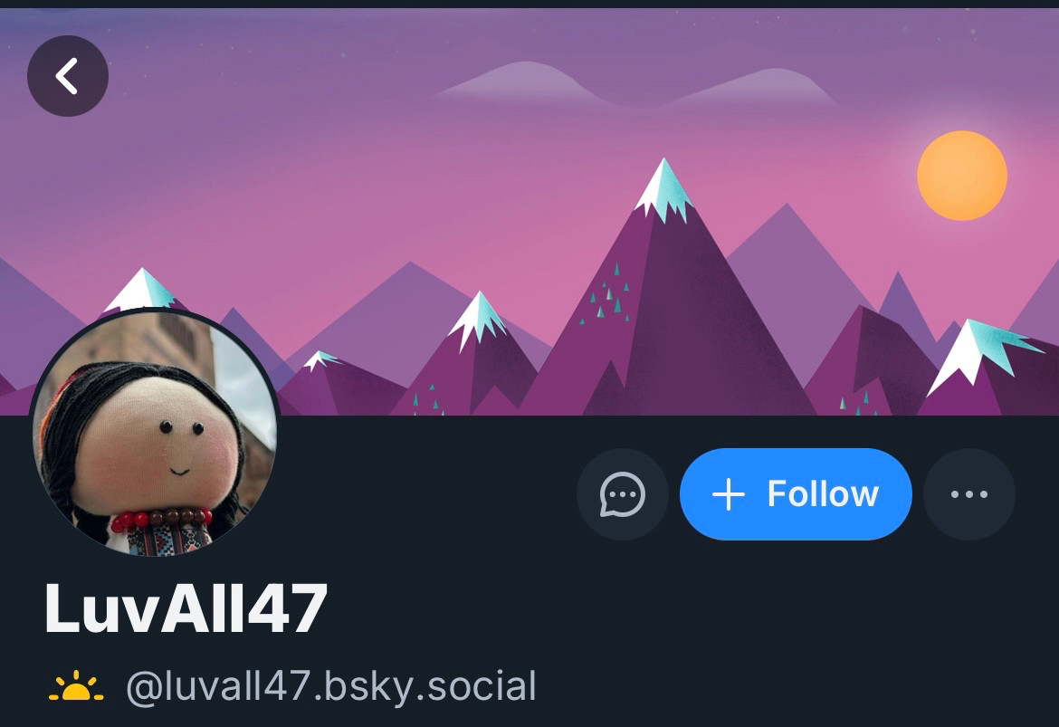 LuvAll47’s profile picture and banner. The banner is a graphic of snow-capped purple mountains and sky with a yellow sun; the profile picture is of a round-faced doll.