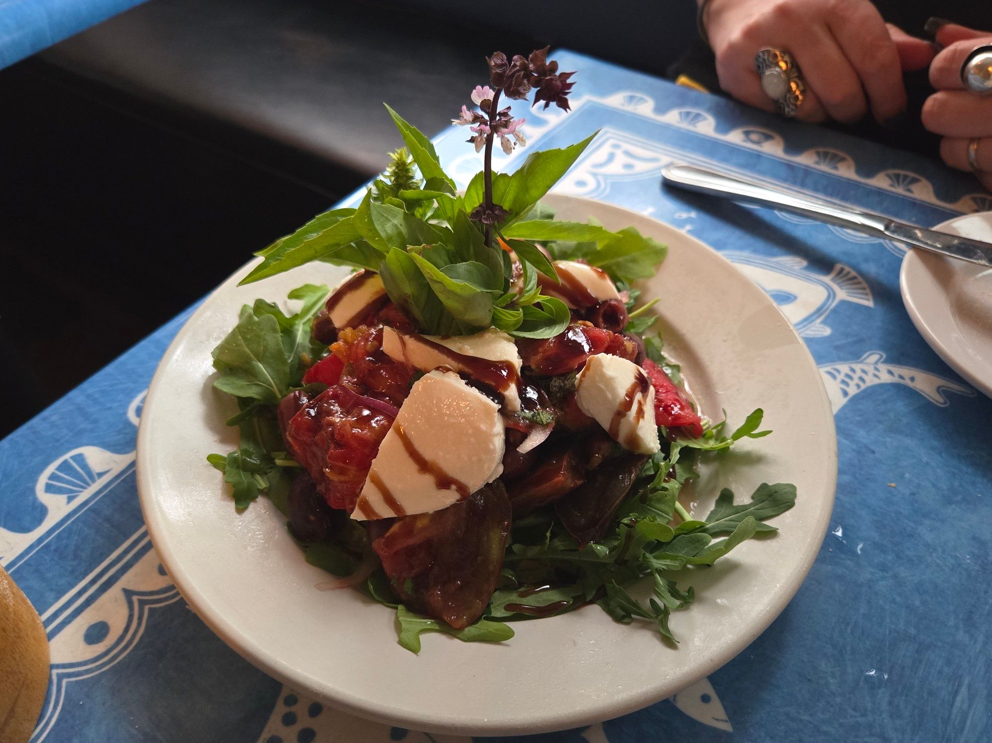 An heirloom tomato and roast beet salad with mozzarella and balsamic vinaigrette, garnished with flowering basil.