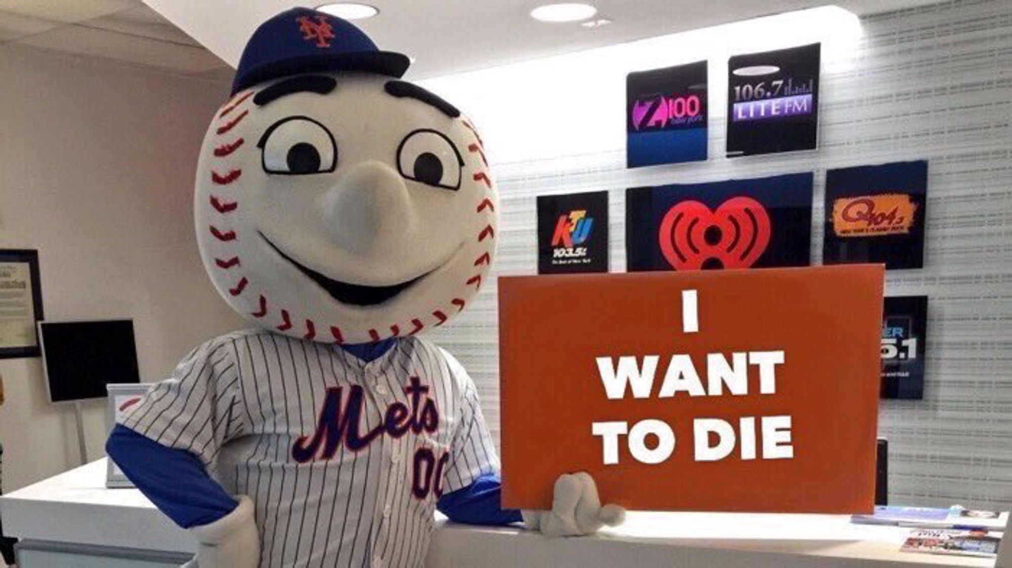 Mr. Met holding a sign that says I WANT TO DIE