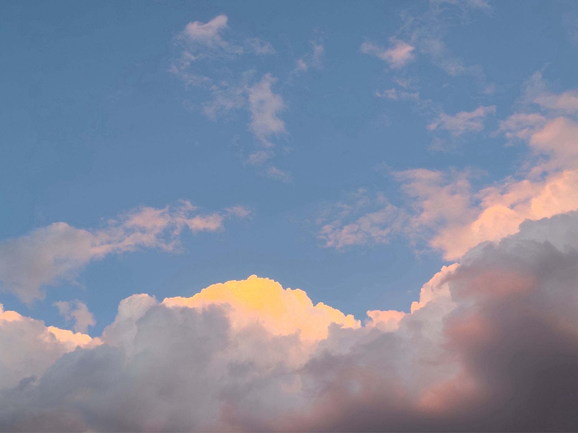 Clouds at sunset, showing a variety of white, pinks, yellows, and white against a blue sky