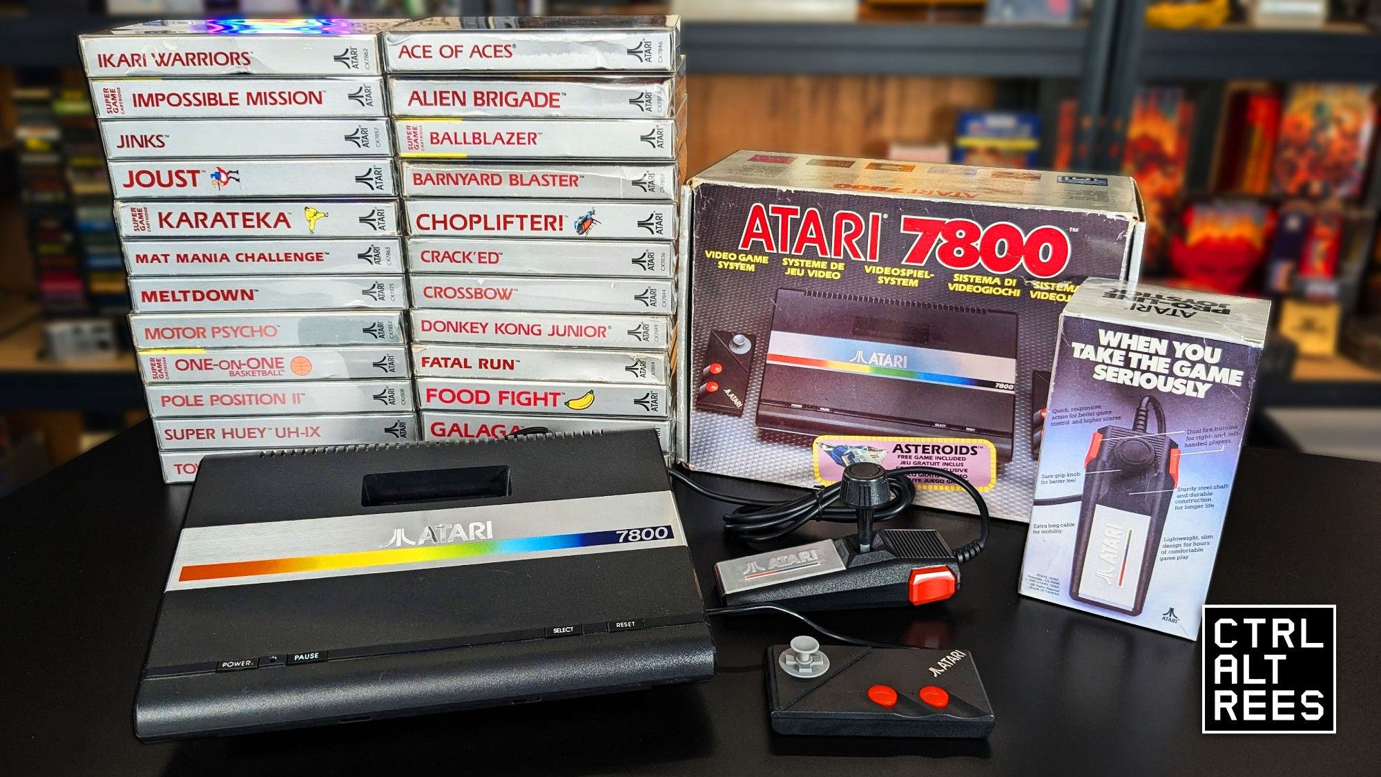 An Atari 7800 console on a desk with a big pile of games