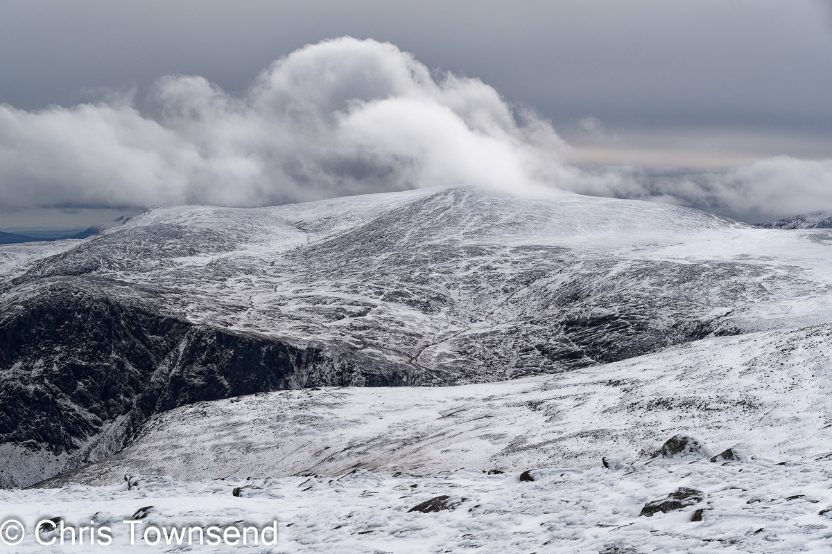 Mountains with snow and cliffs below a cloudy sky