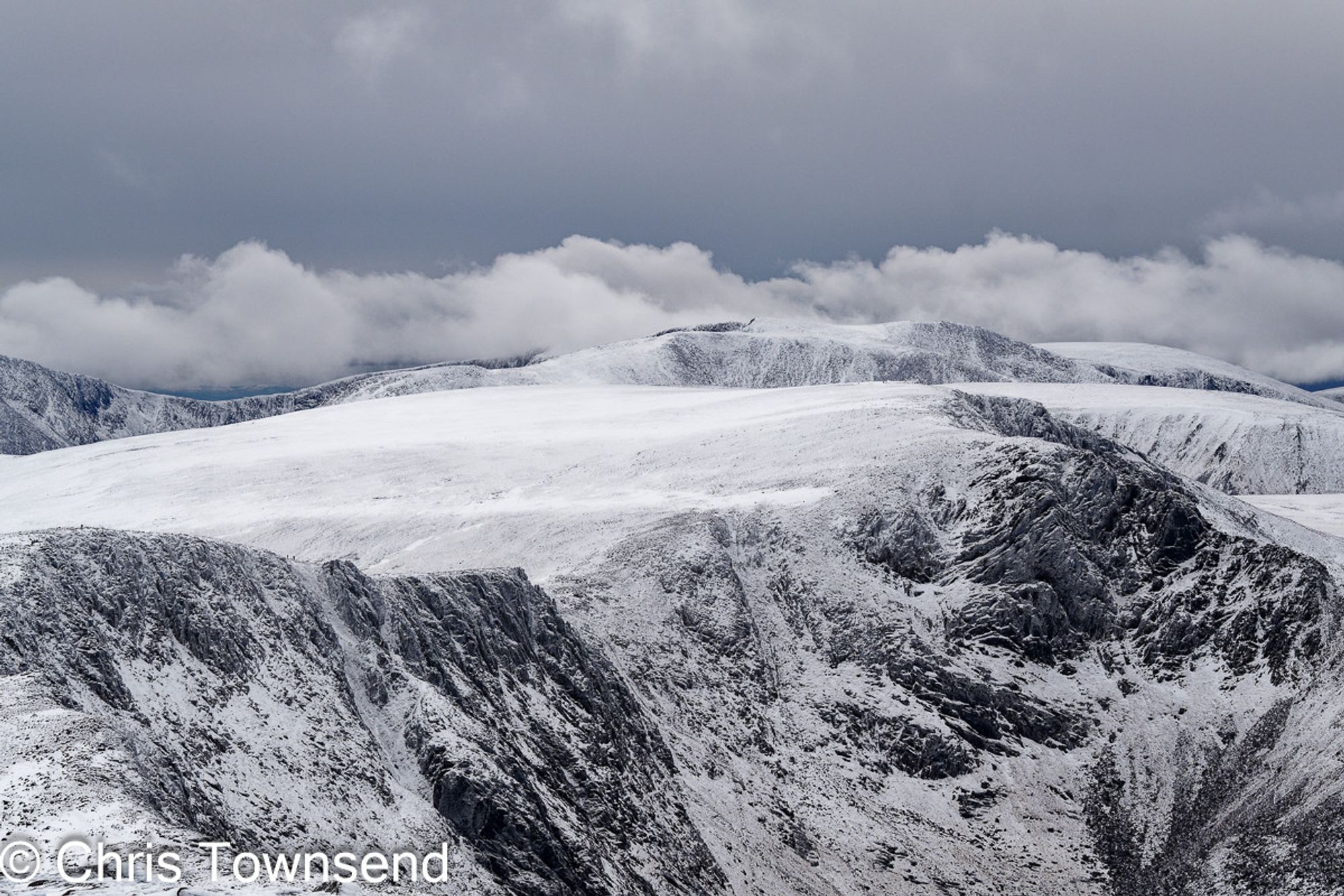 Mountains with snow and cliffs below a cloudy sky