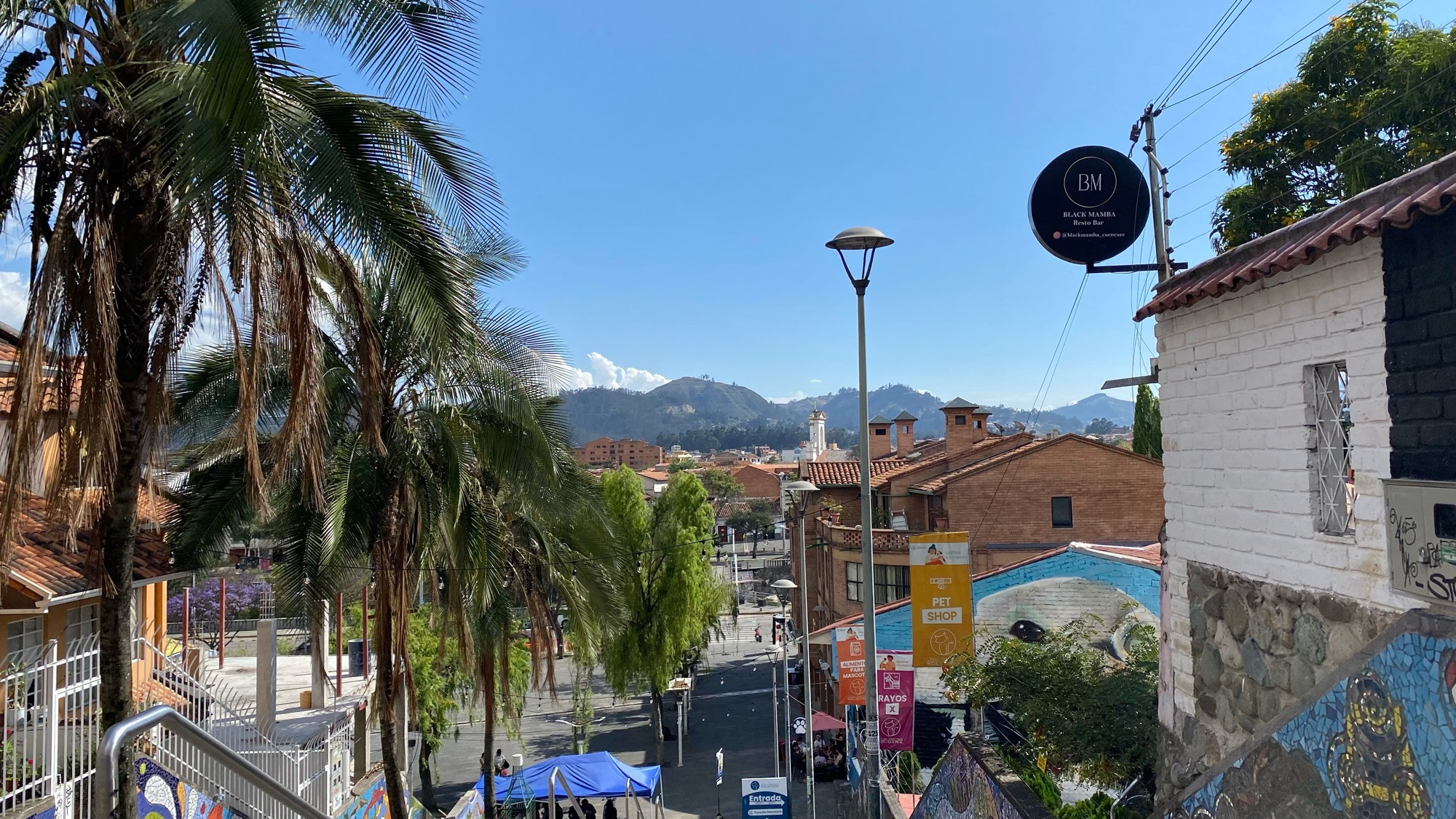 some of the mountains that surround cuenca can be seen from the top of a set of steps. there’s half a city in between the camera and them