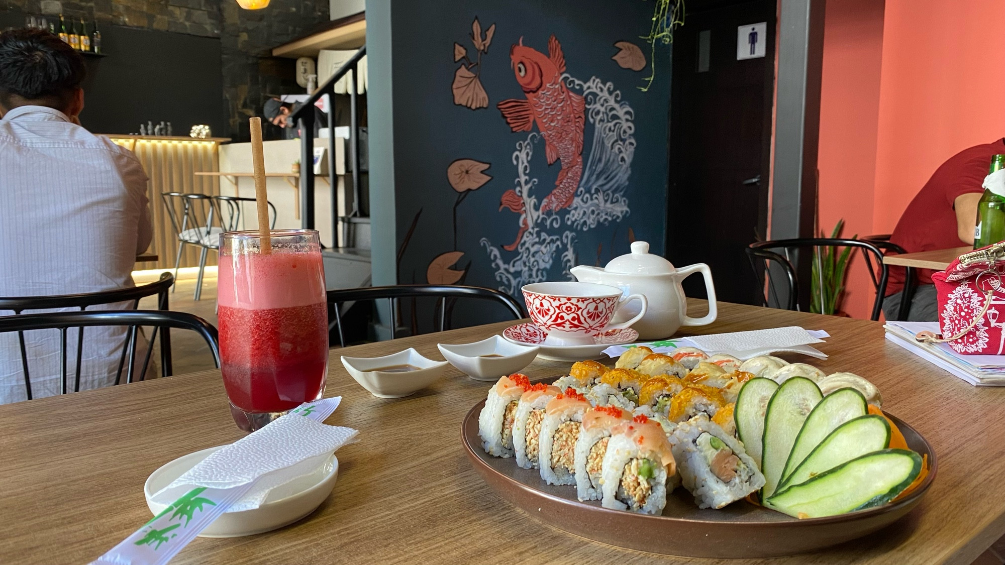 sushi, tea, and juice, with a leaping koi painted on the wall in the background 