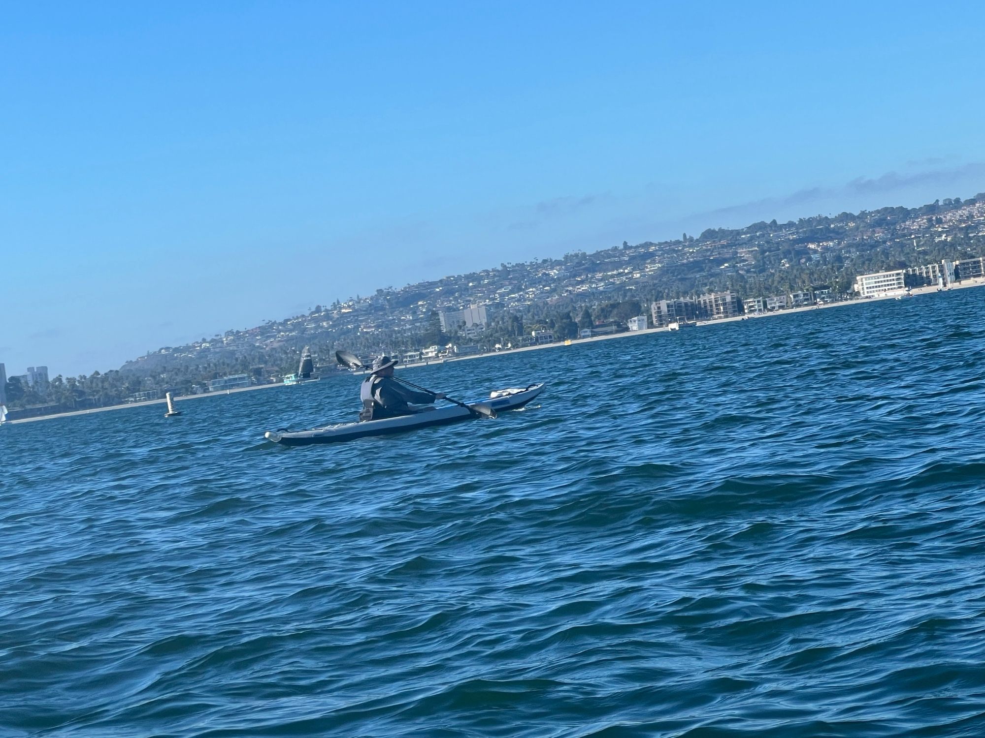 My husband dressed all in gray with a gray hat inside a gray inflatable kayak