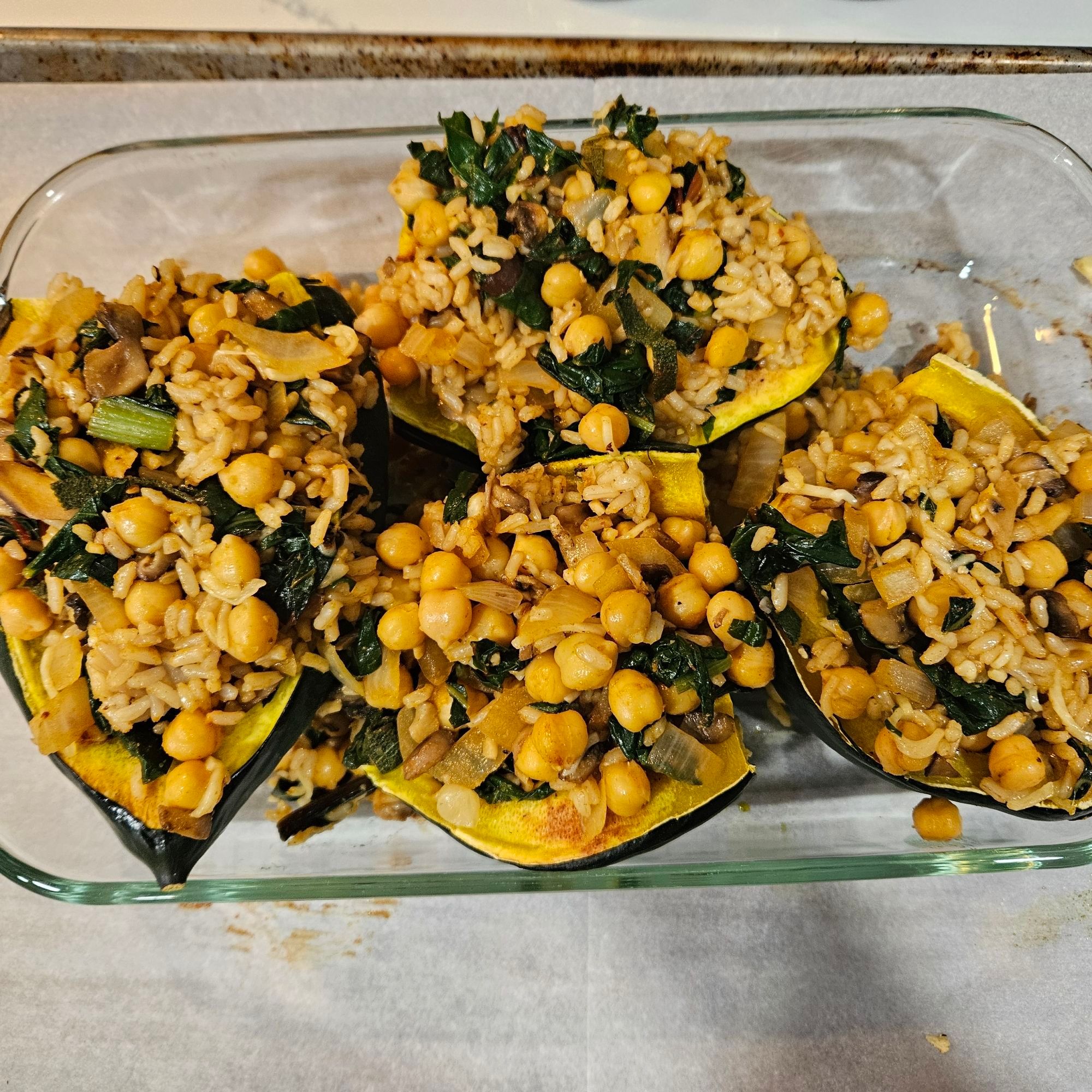 4 halved acorn squash stuffedbwith veggies including wilted chard, onion, garlic, mushrooms, chickpeas and rice.