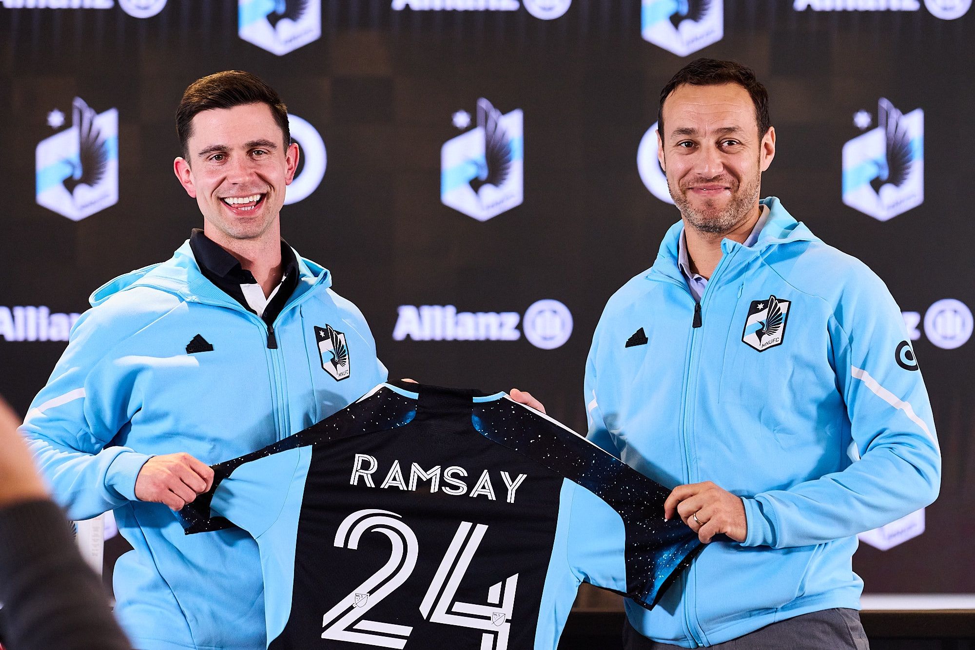 MNUFC head coach Eric Ramsay and sporting director Khaled El-Ahmad present a jersey that says "Ramsay" and number 24.