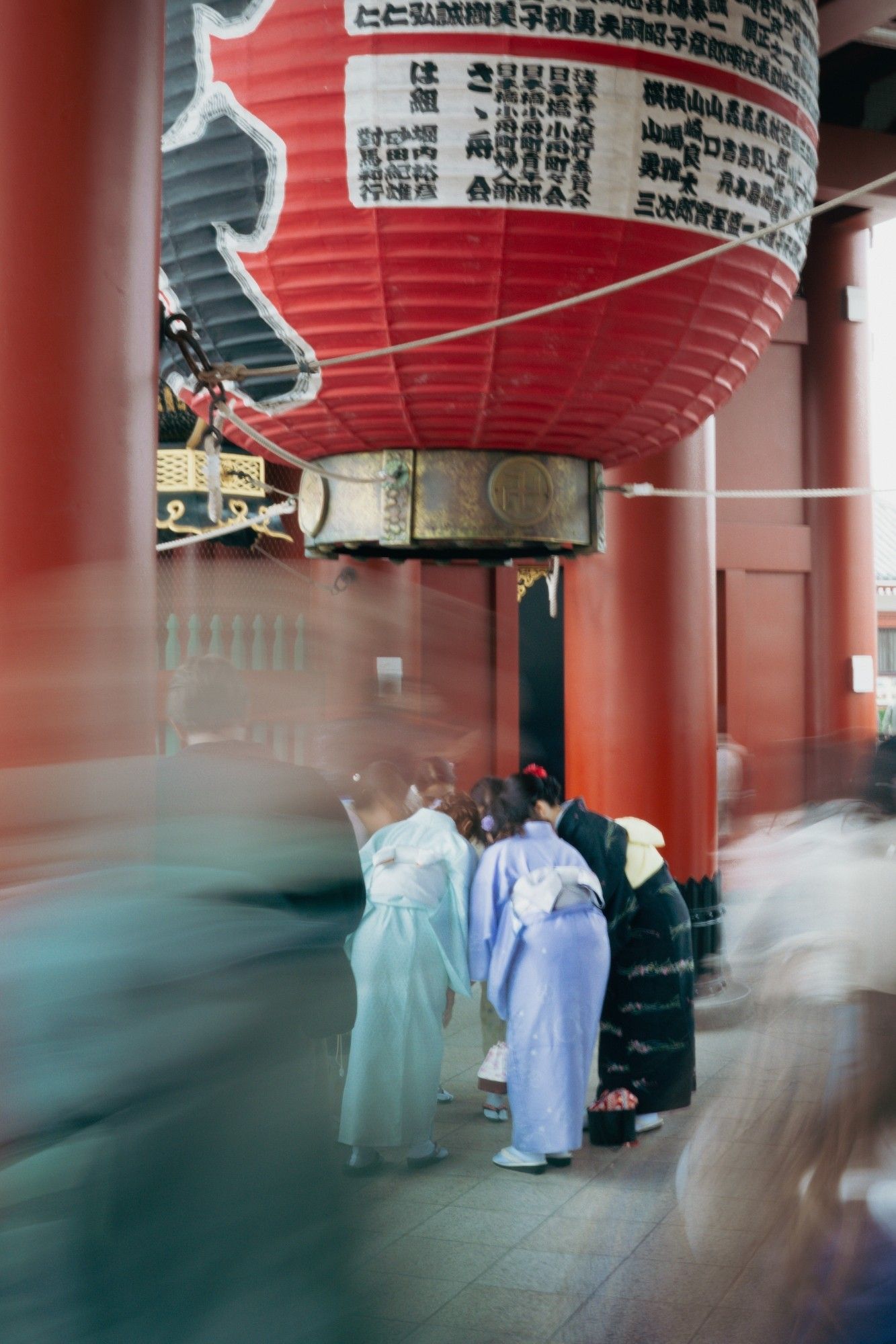 Mulheres de kimono se reclinam para tirar uma selfie, em meio à multidão, abaixo da grande lanterna do portão Kaminarimon no templo Sensoji
Tóquio, Japão, 2024.