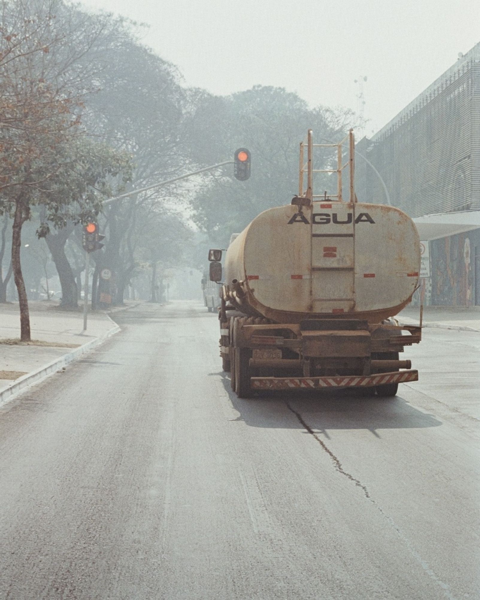 Caminhão de água parado em frente ao sinal vermelho na avenida W3 tomada pela fumaça.