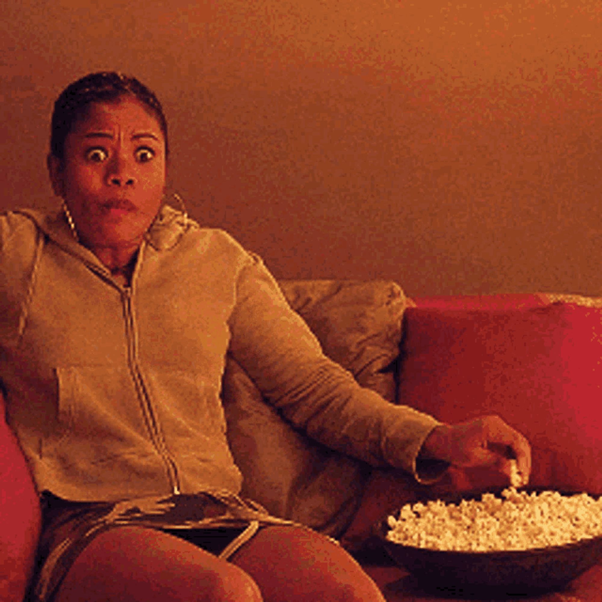 Meme from "Scary Movie," of person eating popcorn while looking intensely at screen while sitting on couch.