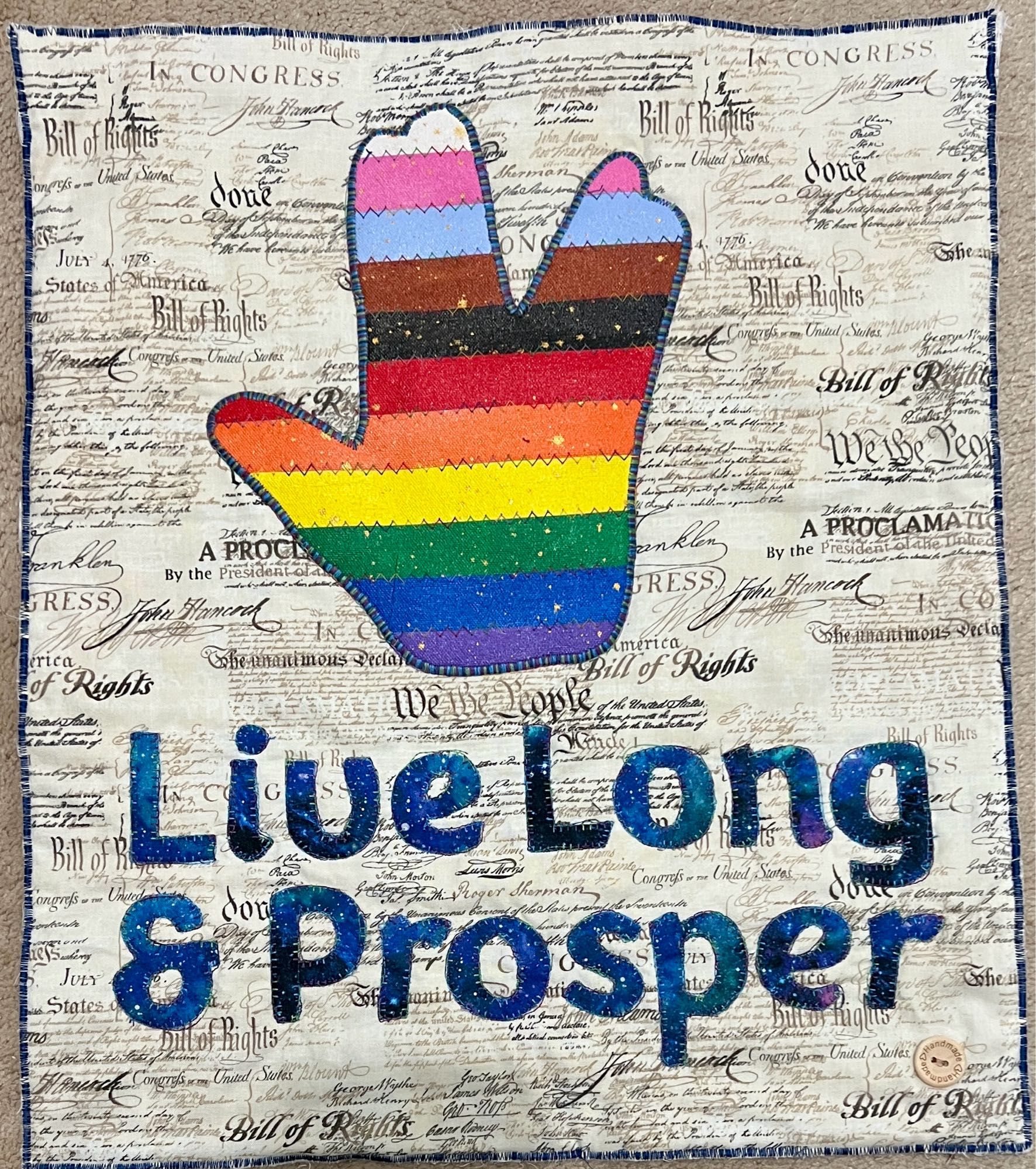 Vulcan Salute cut from acrylic canvas in rainbow with the text live long and prosper in blue fabric