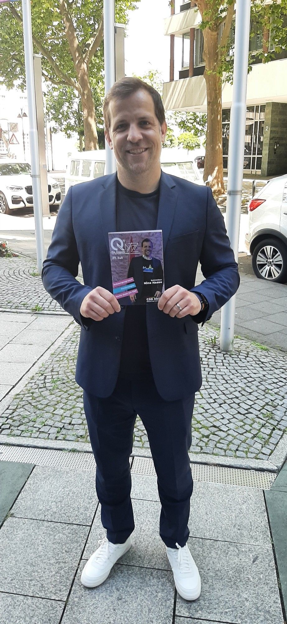 OB Nino Haase als Schirmherr des CSD Mainz mit dem Programmheft auf dem sein Portrait zu sehen ist.