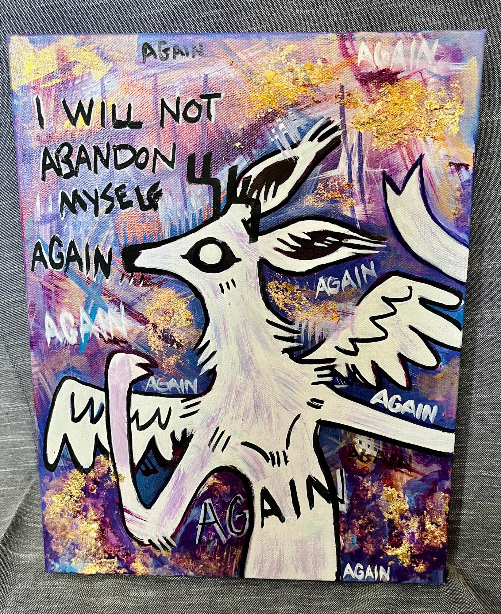 A white one eyed winged deer with arms outstretched surrounded by writing “I will not abandon myself again” with the word again scrawled many times across the canvass