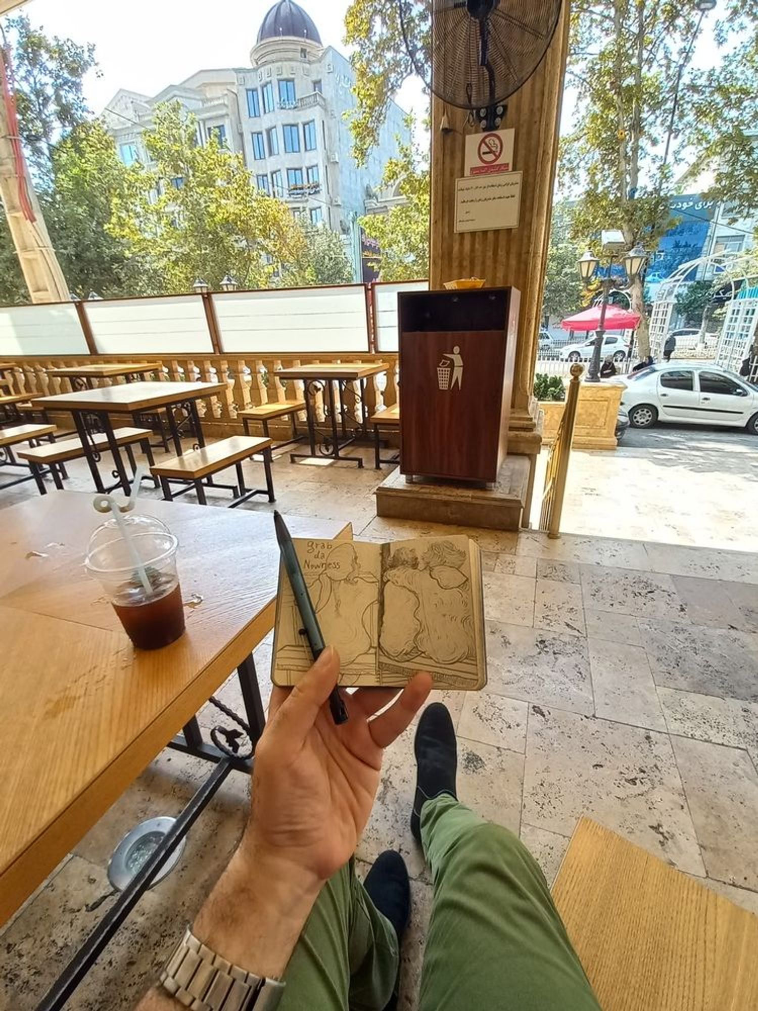 Alt text: This is the café where I often spend time sketching and watching people. On the day I was observing those twins and thinking about my idea, I was here, drawing them. Also that is a page from my notebook from that day.