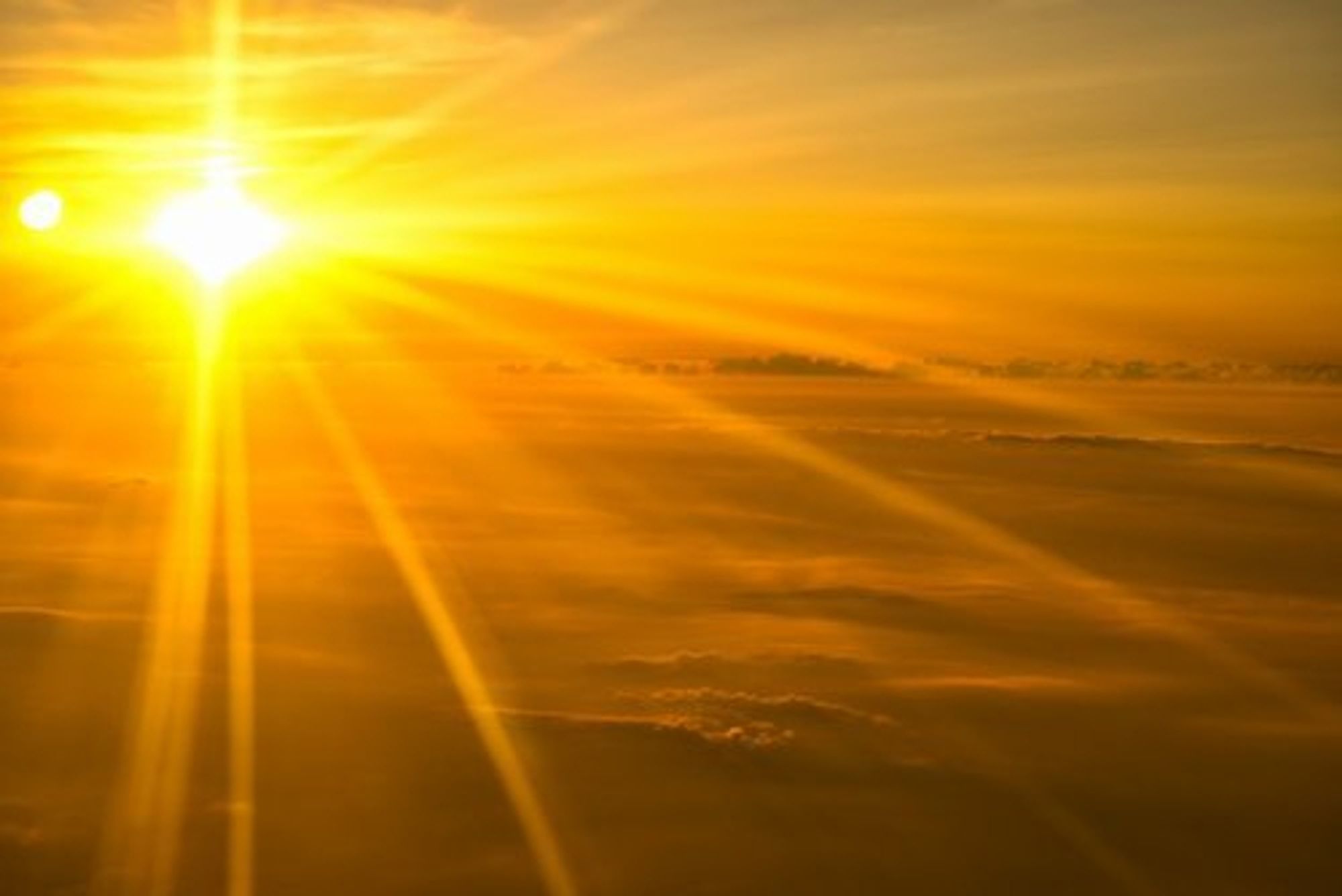 A dazzling morning sun casts golden rays out over ocean waves