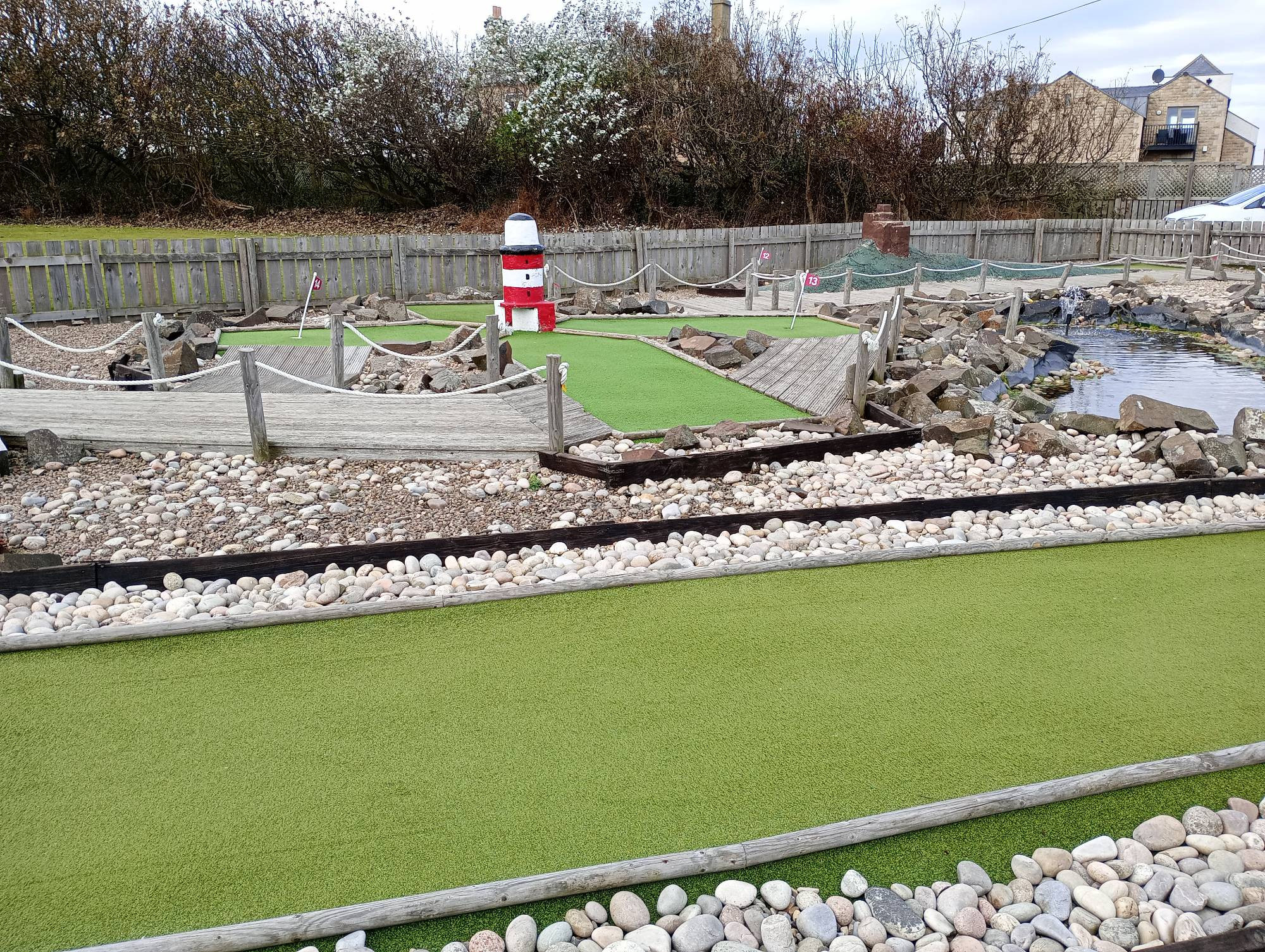 A hole on a mini-golf course with a model lighthouse in the middle