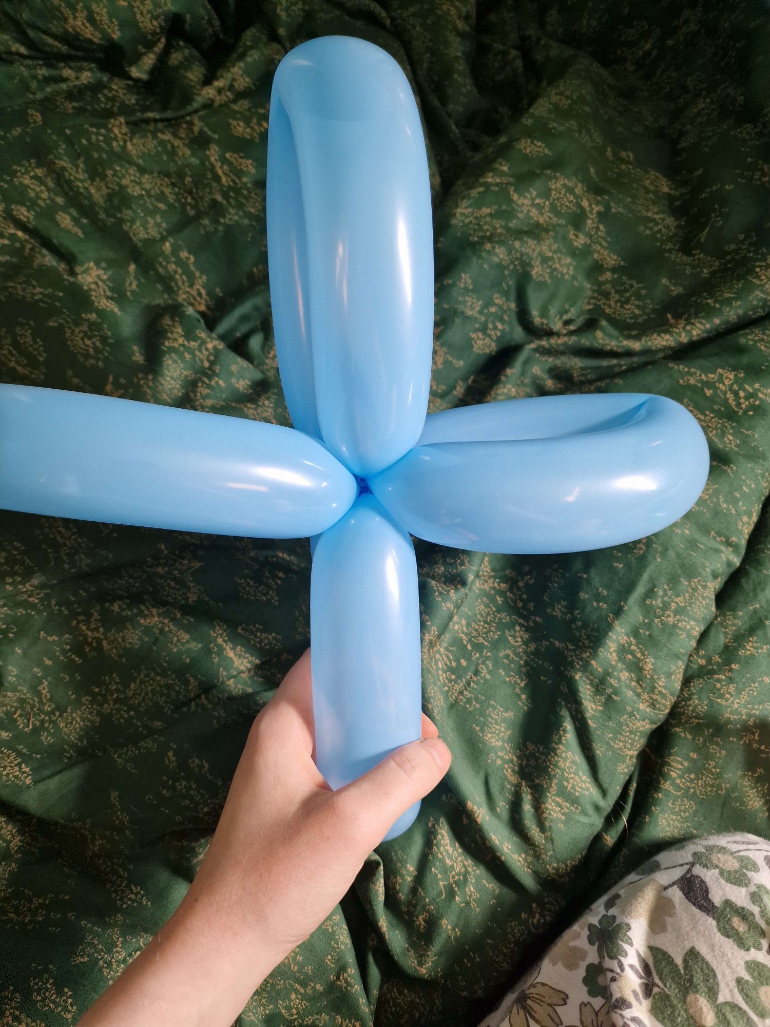 A long balloon twisted into the shape of an equal armed cross