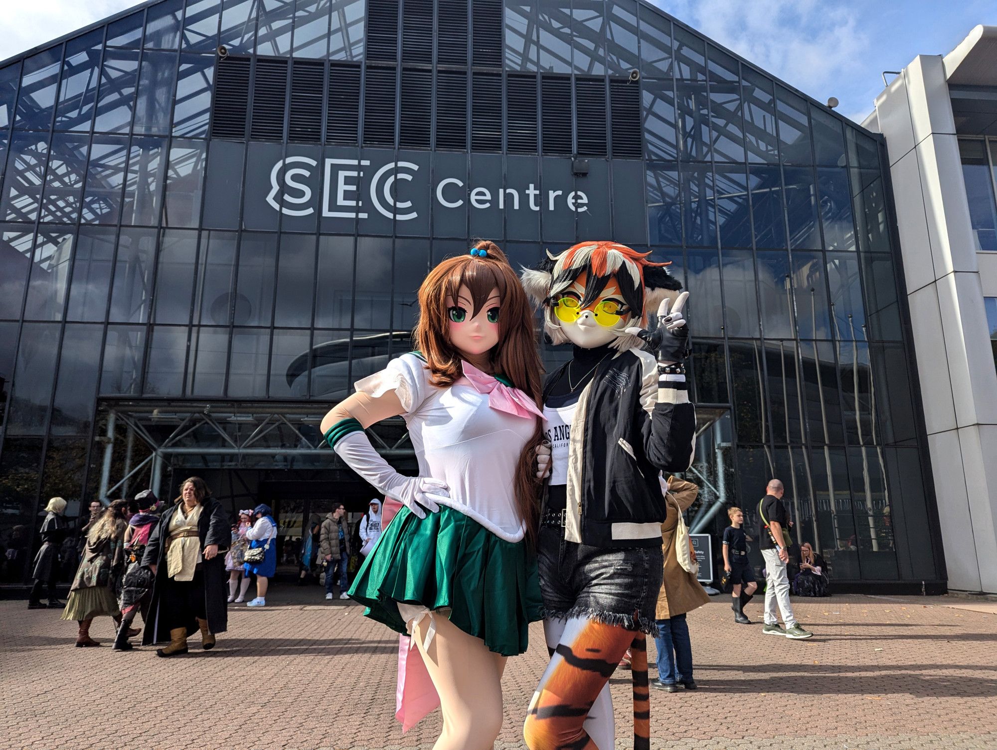 Two kigurumi characters standing in front of the SEC Centre, posing for the camera: the tiger girl Waai Fu, and Sailor Jupiter.