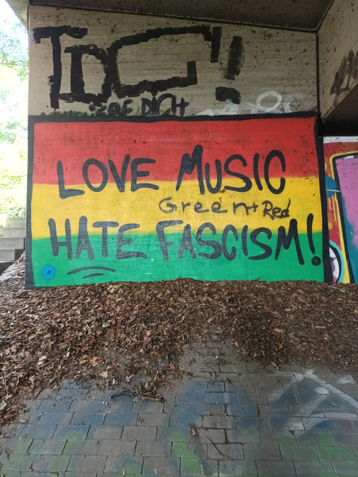 Graffiti unter der Brücke am Ruhrstadion.
Grün-gelb-roter Hintergrund und der Schriftzug love music hate fascism