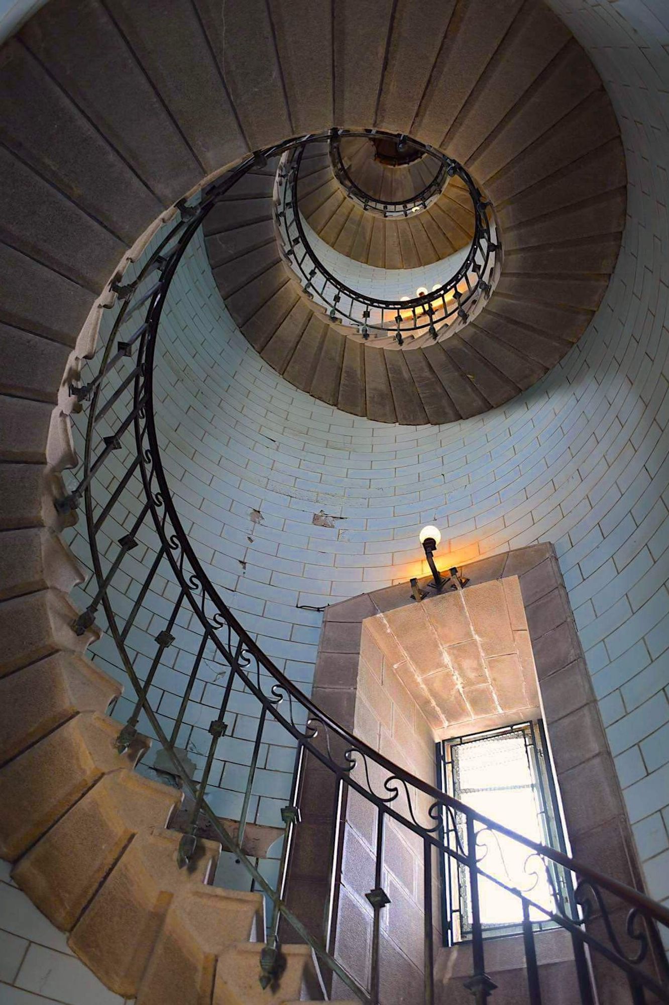 Escalier en spirale du phare d'Eckmühl vu du bas, mur couverts de carreaux d'opaline de couleur bleue