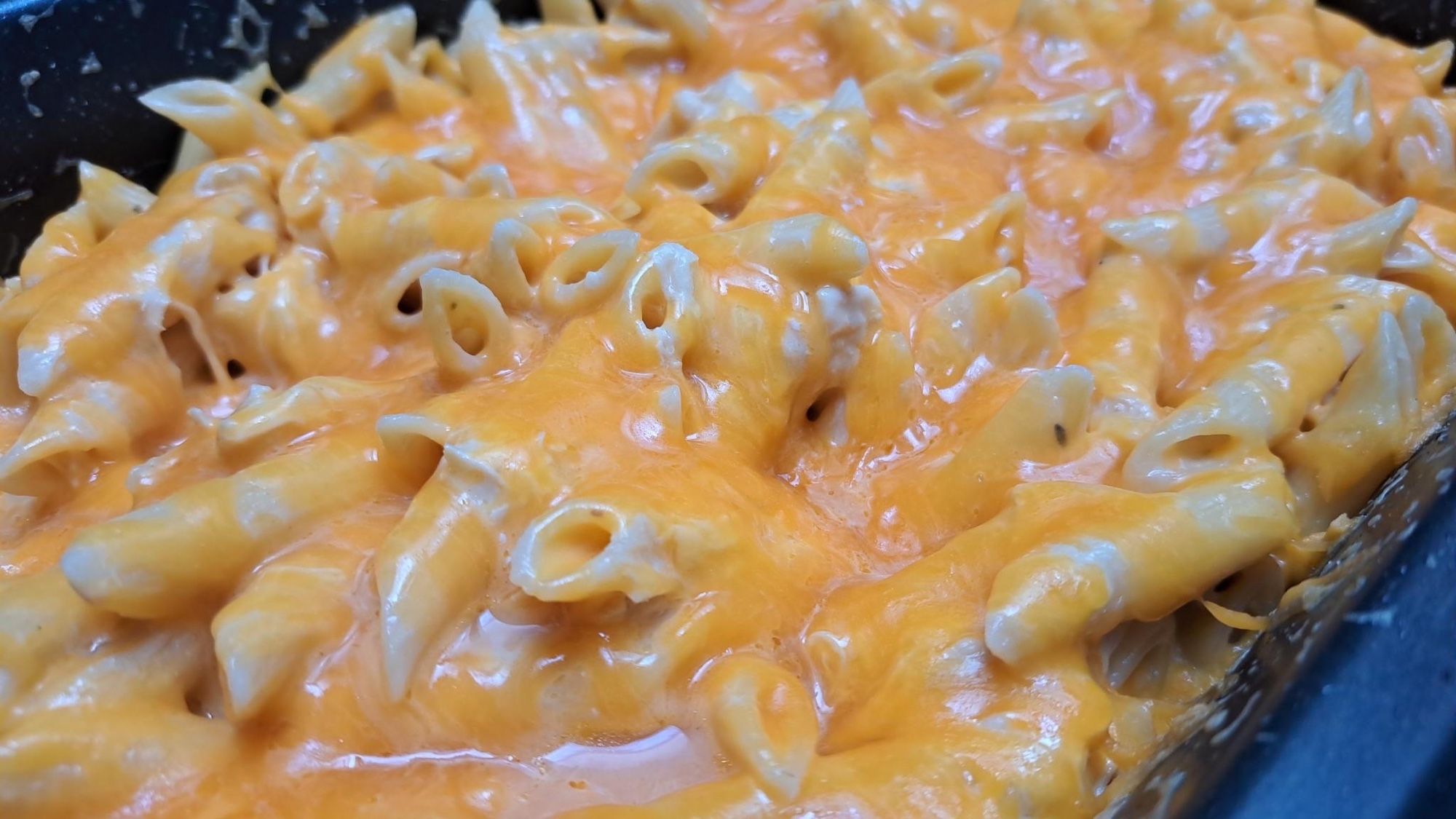 A close up of cheesy penne pasta in a crockpot