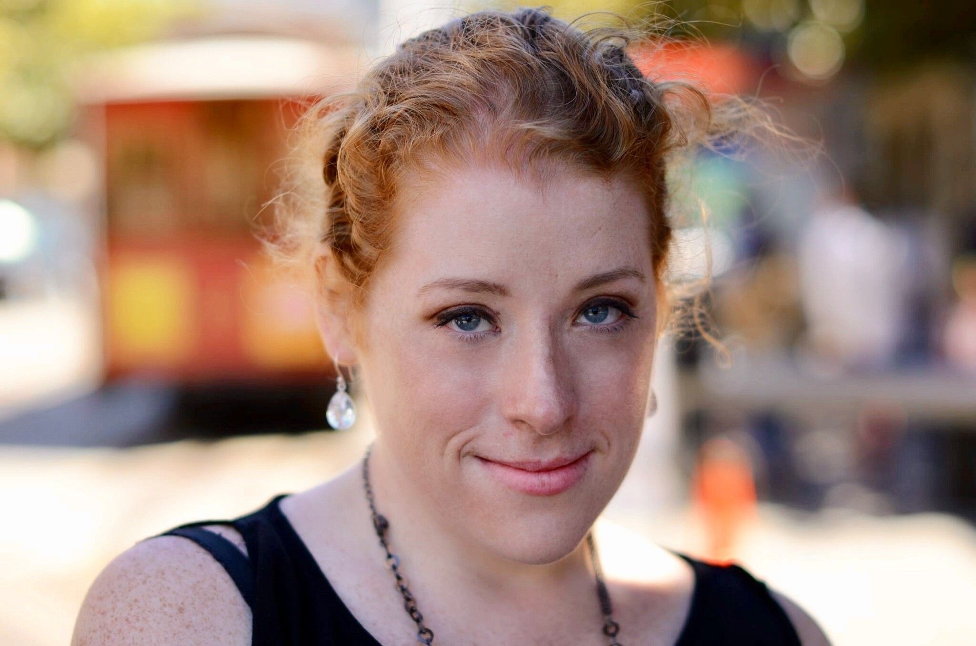 A young lady with red curly hair smiles into the camera.