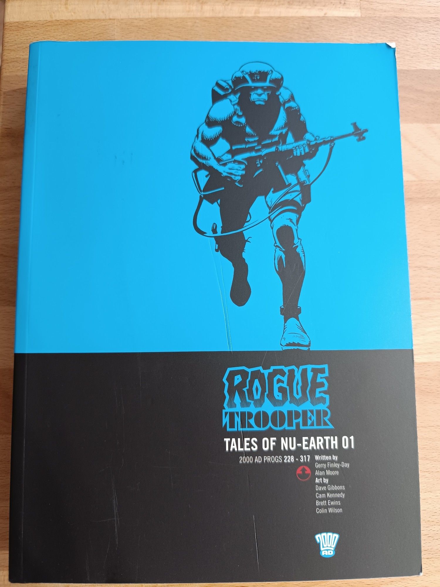 The first Rogue Trooper Collection of comics called "Tales of Nu-Earth 01" from 2000AD, written by Gerry Finley-Day and Alan Moore. The cover is blue on the top an black on the bottom and shows the titular Rogue Trooper, a blue genetic super soldier in military gear and gun.