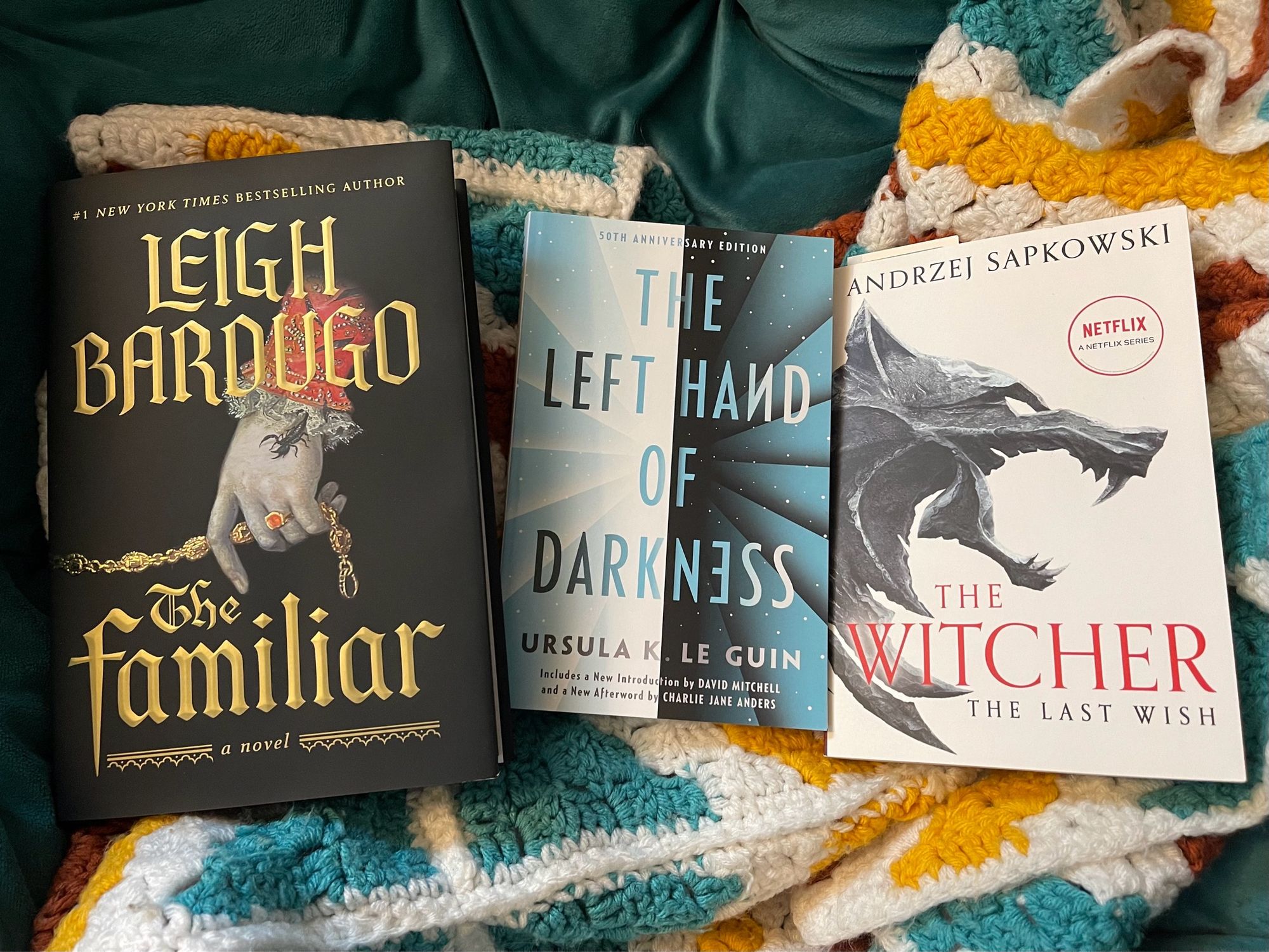 Three books side by side: The Familiar by Leigh Bardugo, The Left Hand of Darkness by Ursula K Le Guin, and The Witcher: The Last Wish by Andrzei Sapkowksi