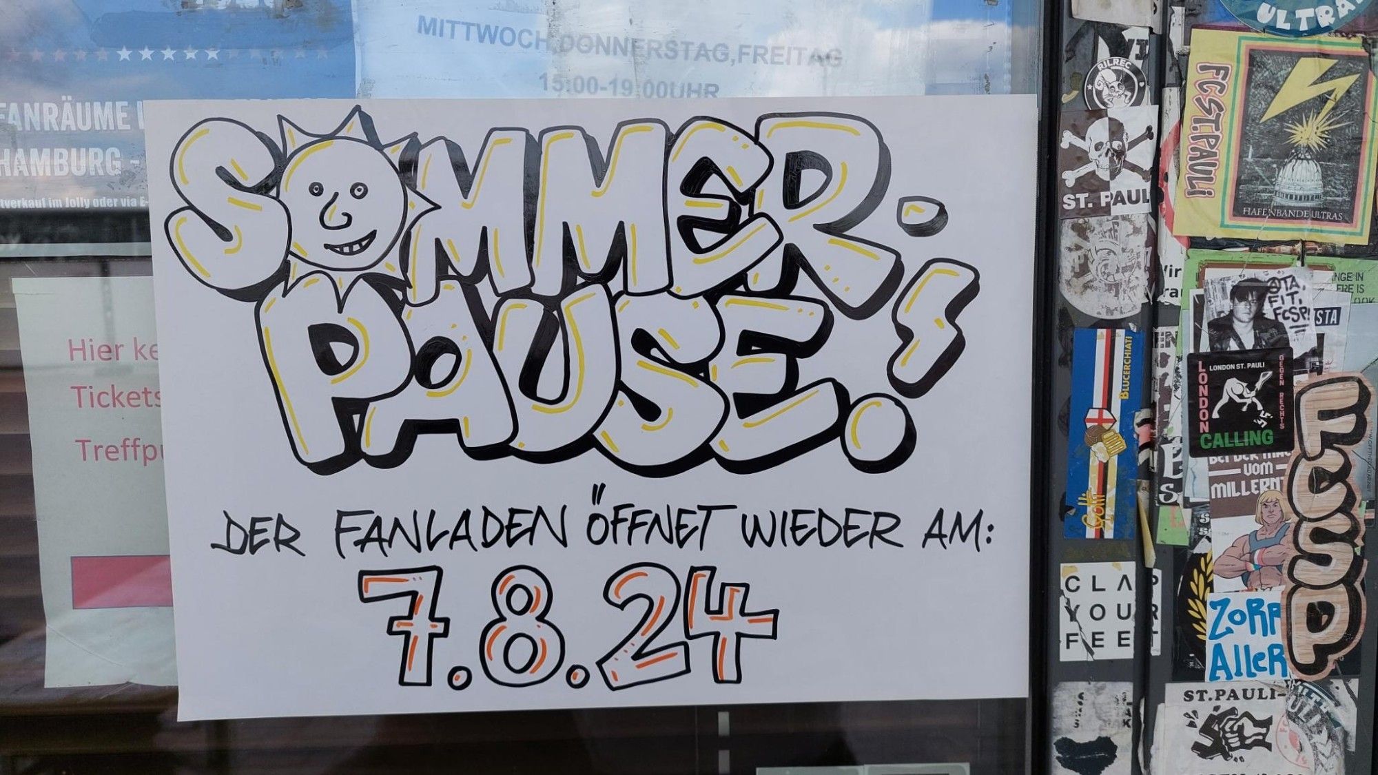 Plakat an der Fanladentür mit der Info, dass der Fanladen am 7. August wieder öffnet