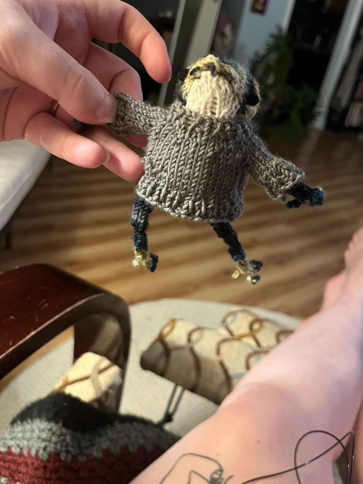 The same small knit frog in a grey/green sweater