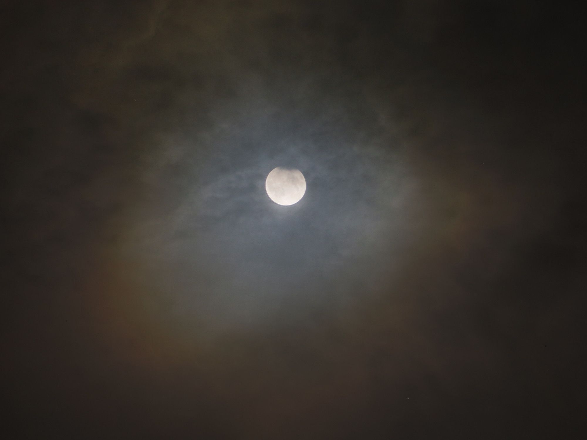 Partial lunar eclipse -- moon in a cloudy sky with a halo