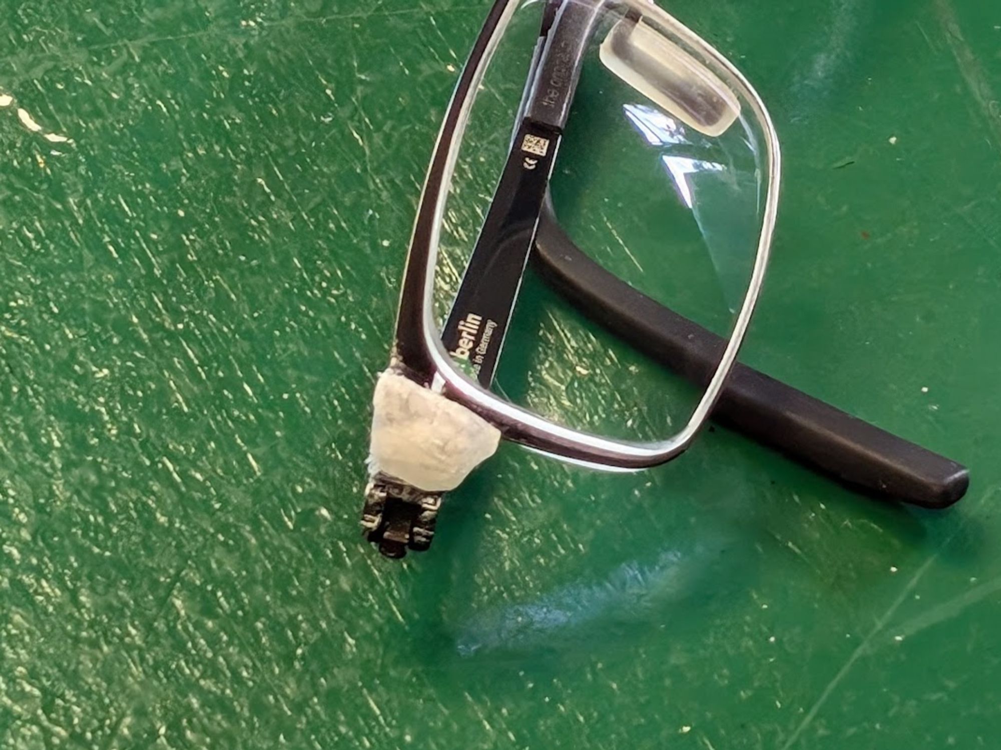 Metal glasses frame with a white patch on one side next to the lenses.