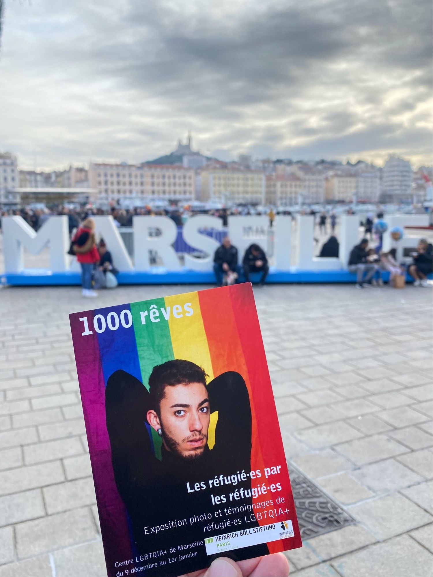 Image de la carte postale de l'exposition devant la silhouette de la ville de Marseille.