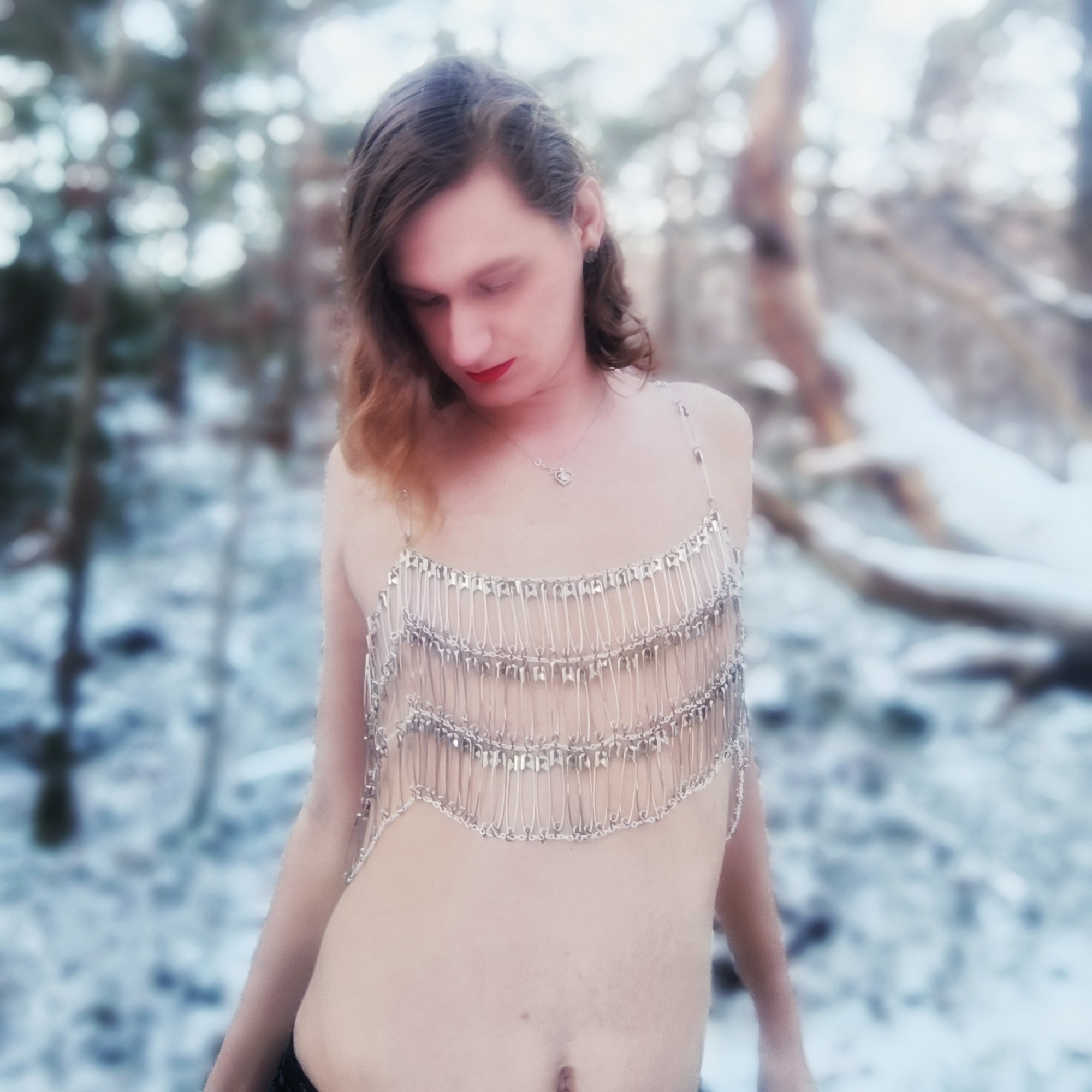 A girl wearing a top made from chains and safety pins in a winter landscape