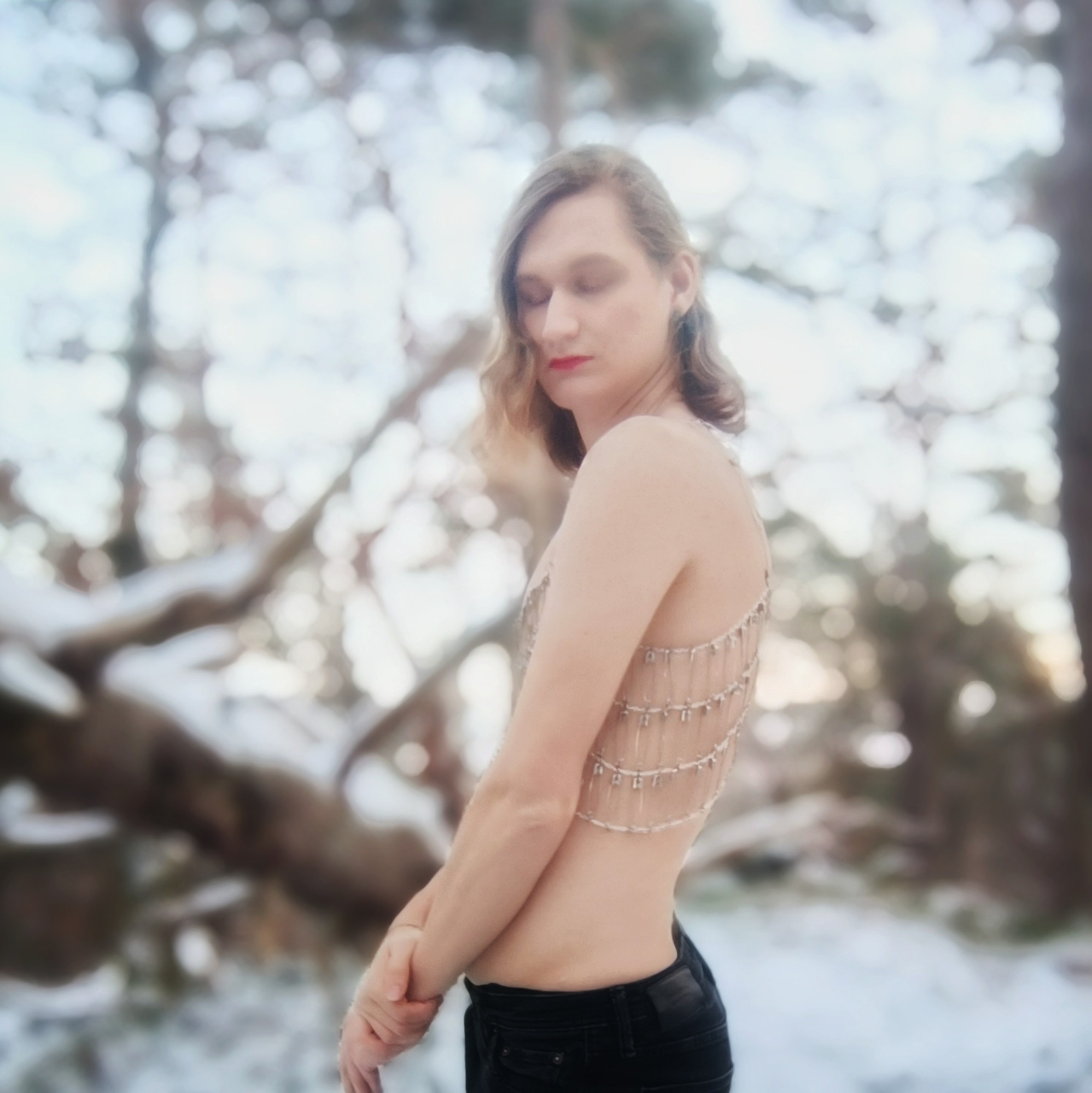 A girl wearing a top made from chains and safety pins in a winter landscape