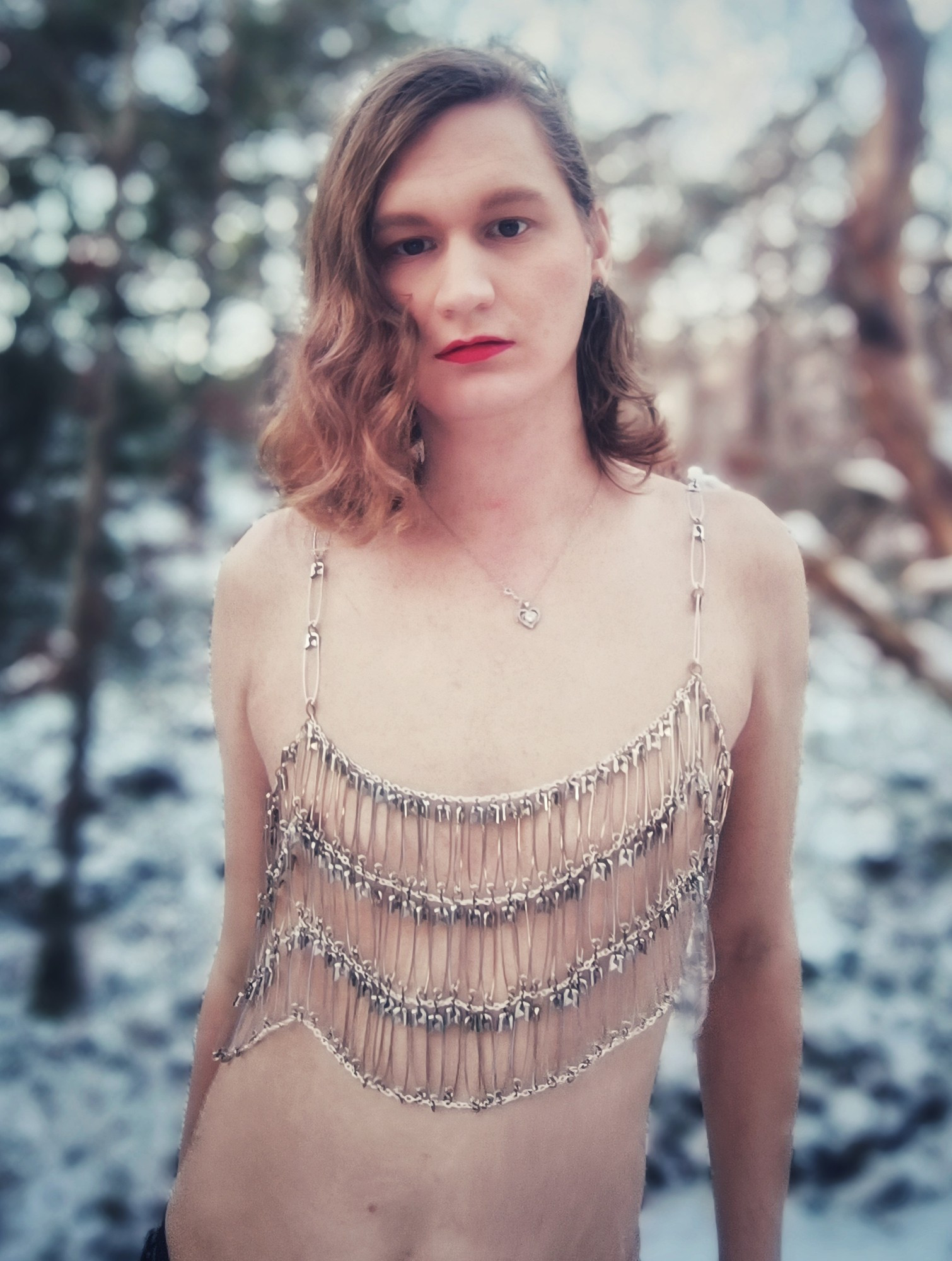 A girl wearing a top made from chains and safety pins in a winter landscape