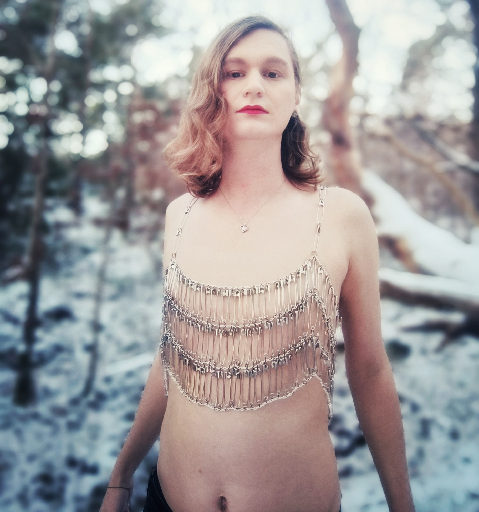 A girl wearing a top made from chains and safety pins in a winter landscape