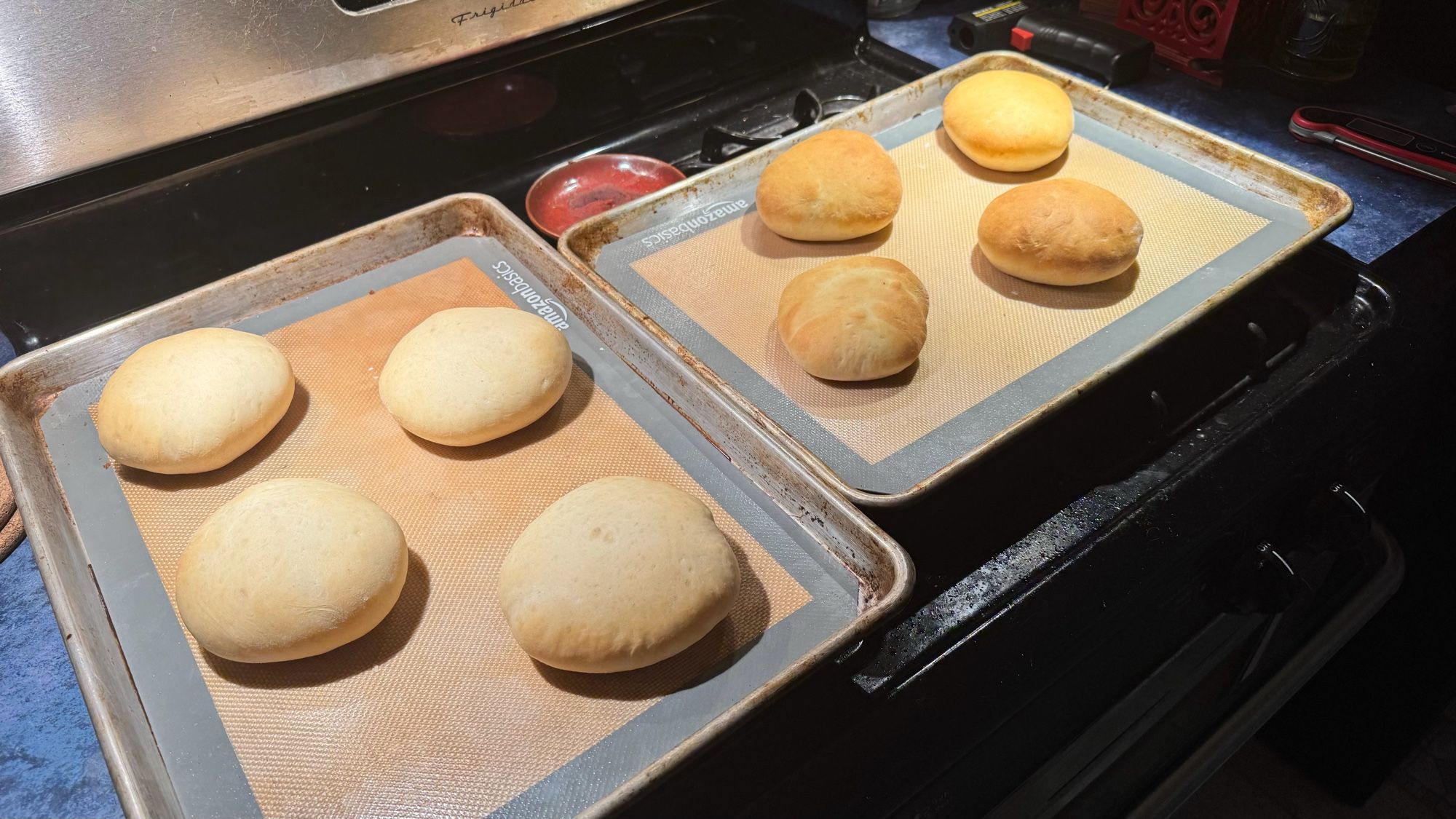 Two sheet pans of homemade hamburger buns, fresh out of the oven.