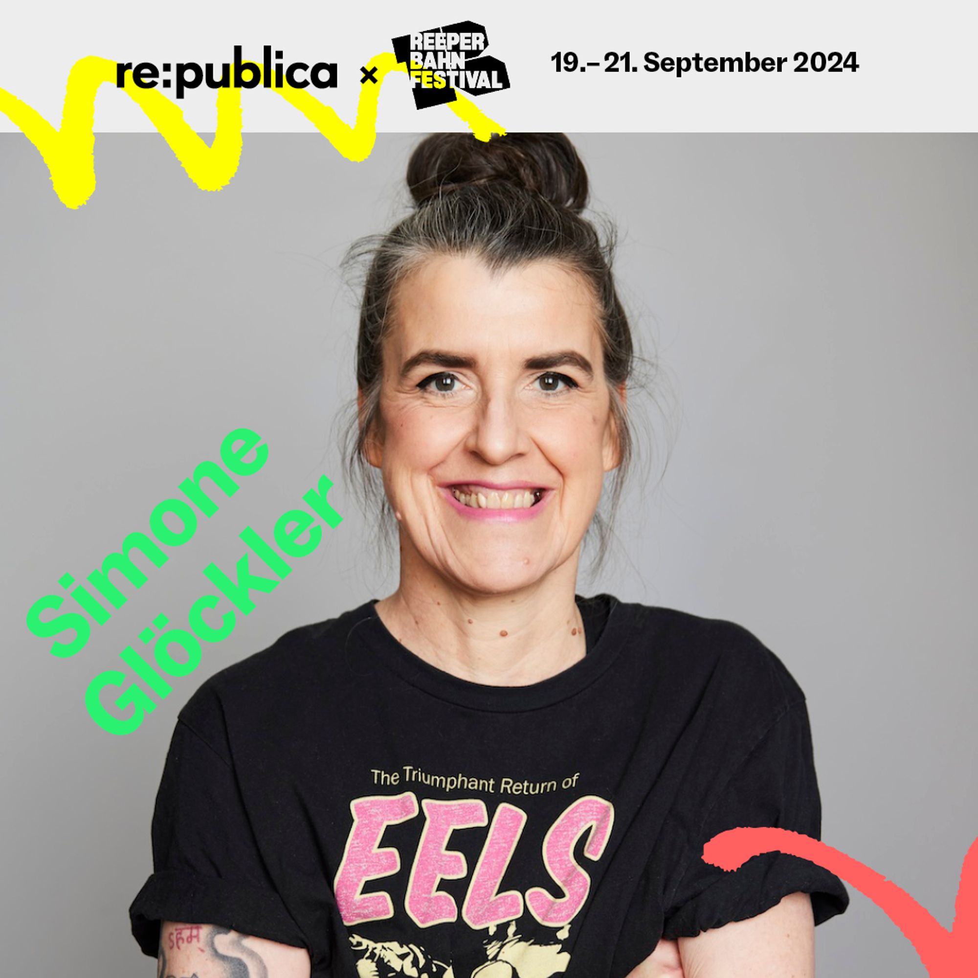 Speaker-Visual mit Simone Glöckler. Eine weibliche Person mit verschränkten Armen lächelt ins Bild, auf ihrem T-Shirt ist der Bandname EELS zu lesen.