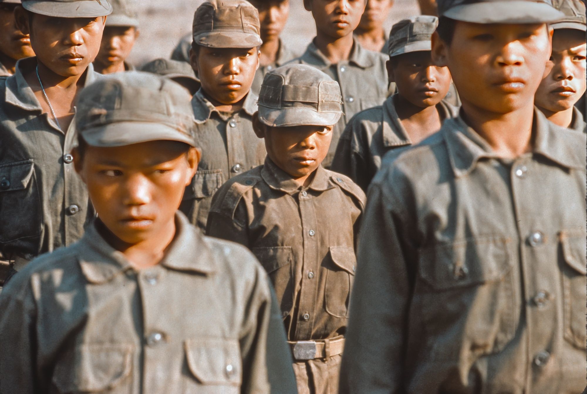 Sad and intimidated, young boy soldiers, the smallest about 10 years old, stand at attention in the camp of an opium warlord in Burma