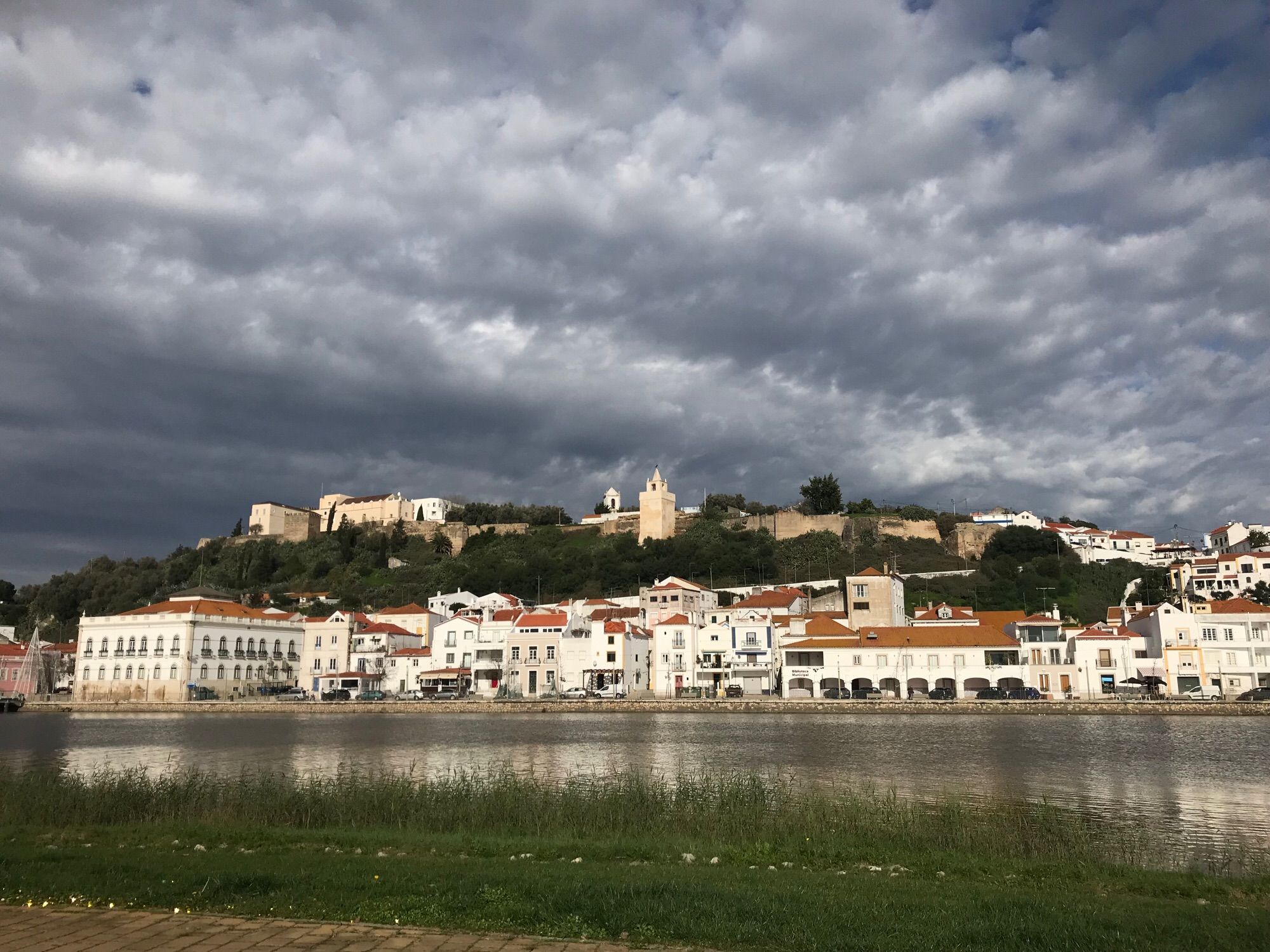 Stadtsilhouette mit weißen Häusern am Fluss, in Portugal. Der Himmel ist bewölkt.