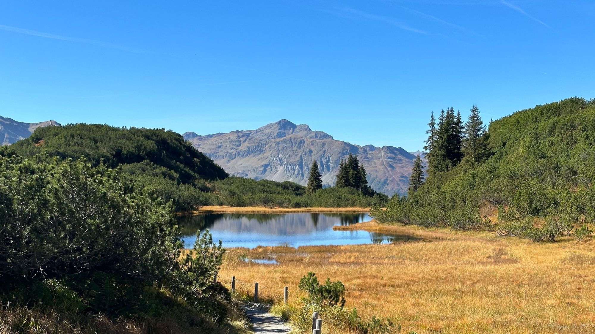 Bergsee unter blauem Himmel in der Sonne.