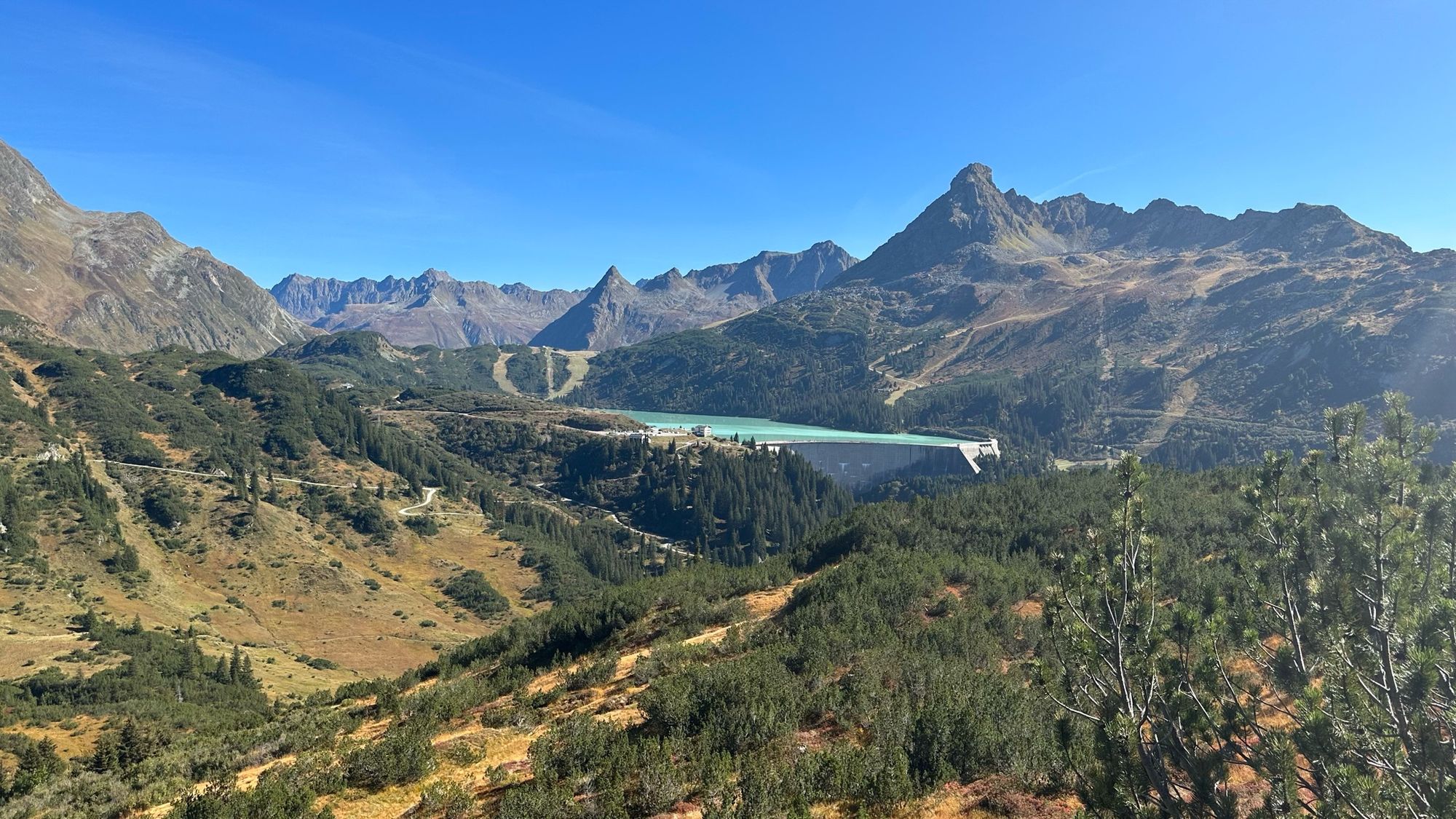 Blick auf einen Stausee in den Alpen. Blauer Himmel.